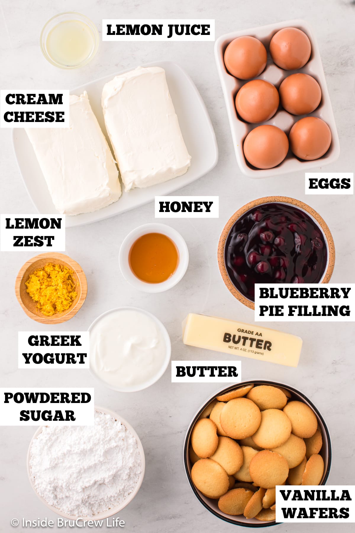 Bowls of ingredients needed to make lemon cheesecakes with blueberry filling.