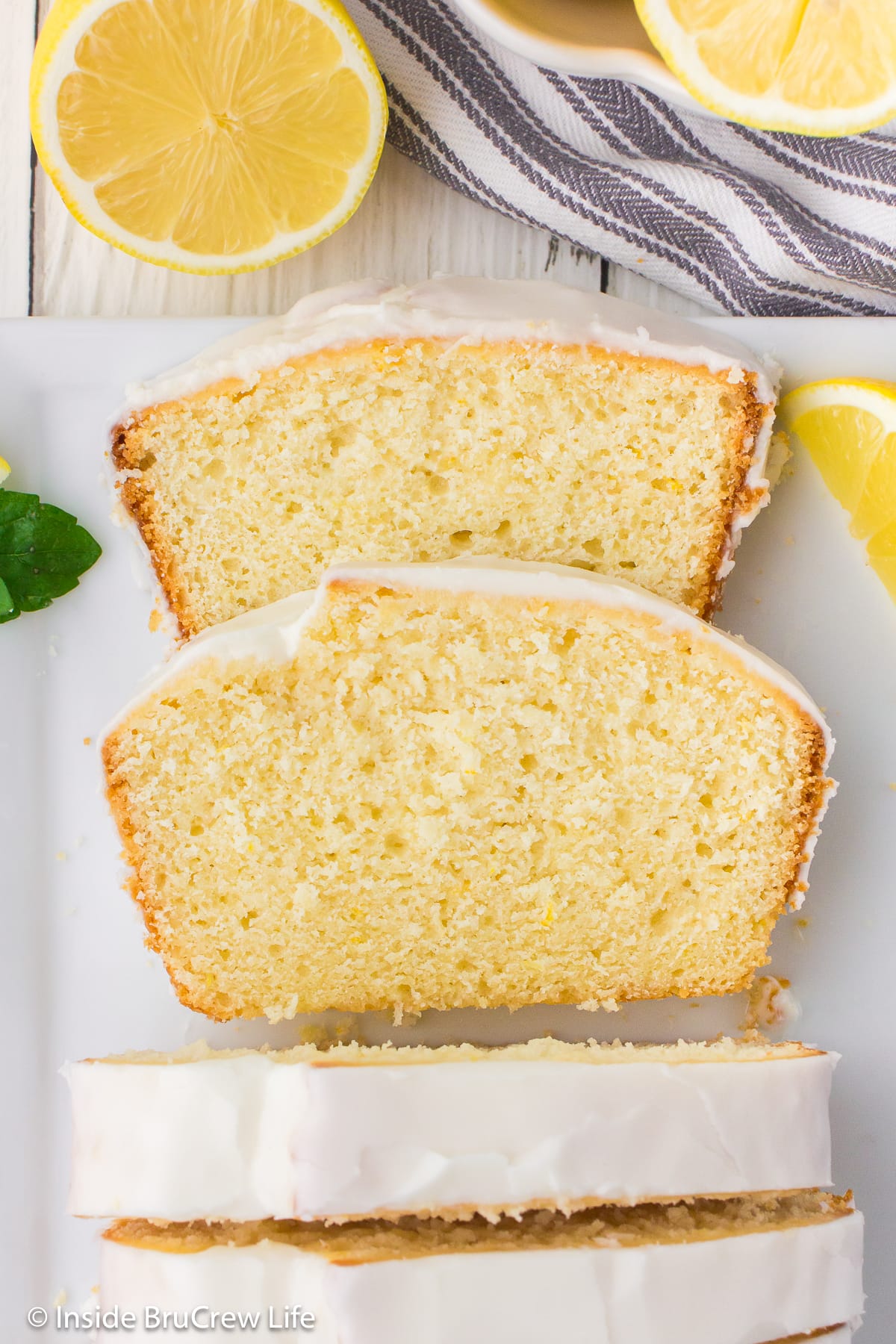 Two slices of lemon loaf cake on a white board.