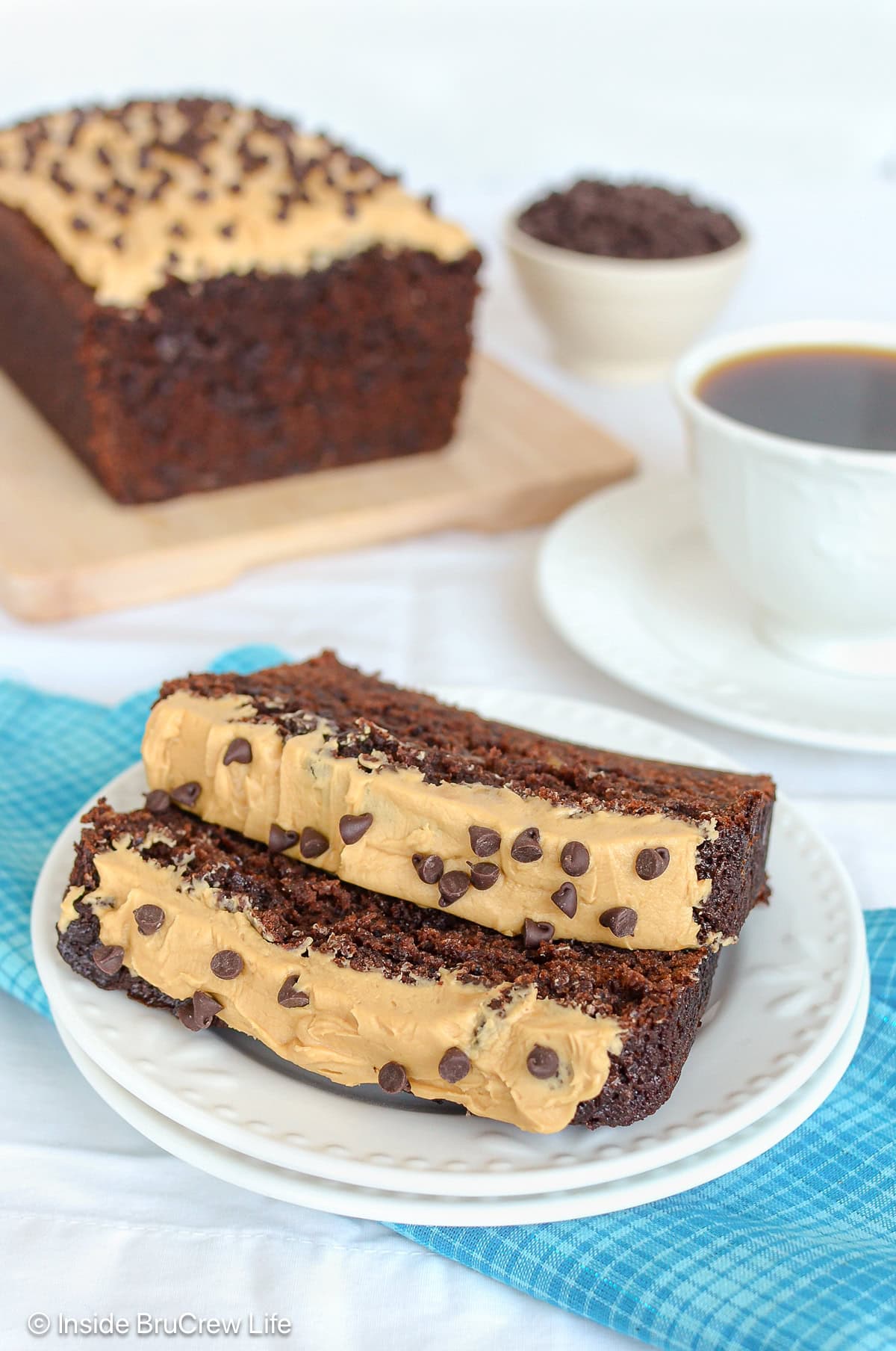 Slices of frosted chocolate banana bread on a white plate.