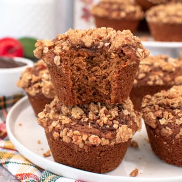 Apple butter muffins stacked on a white plate.