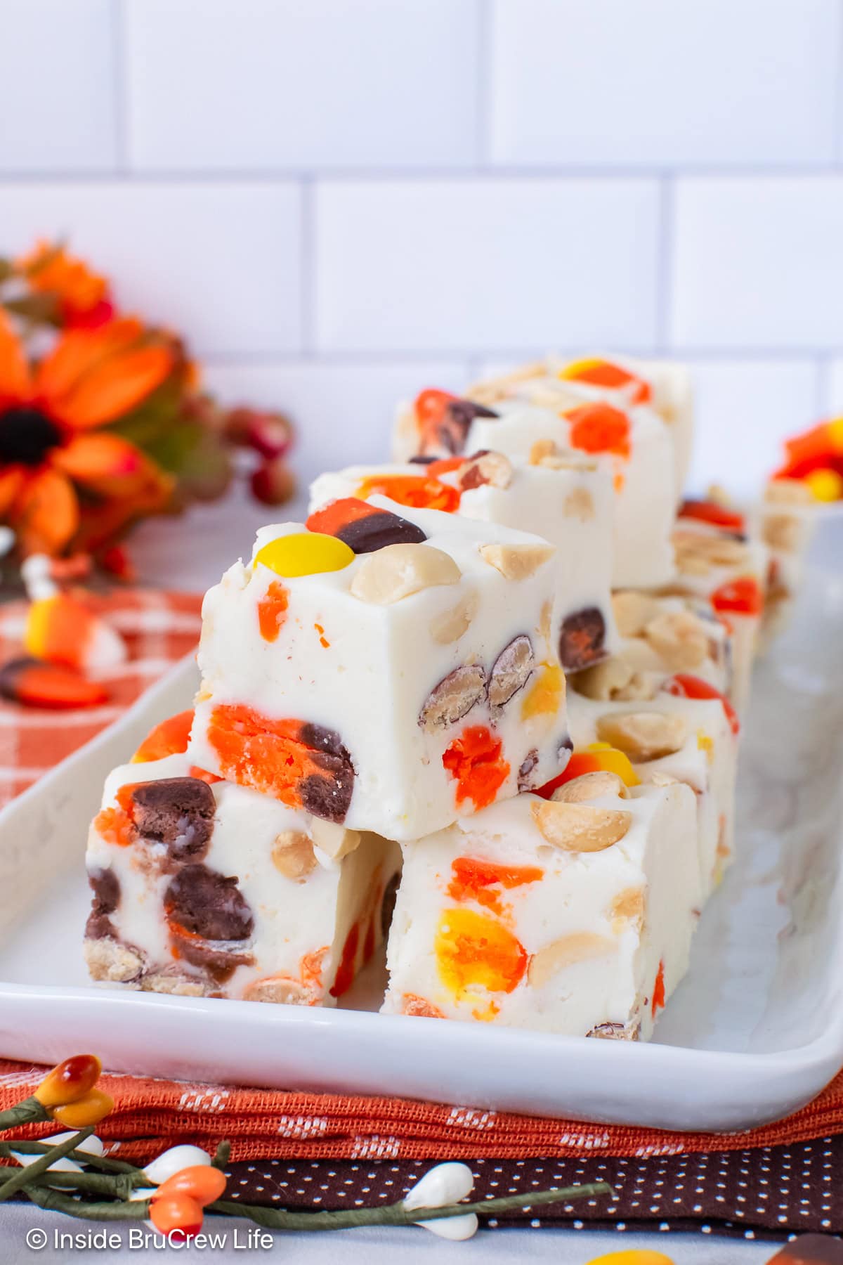 A white tray stacked with white chocolate candy corn fudge.