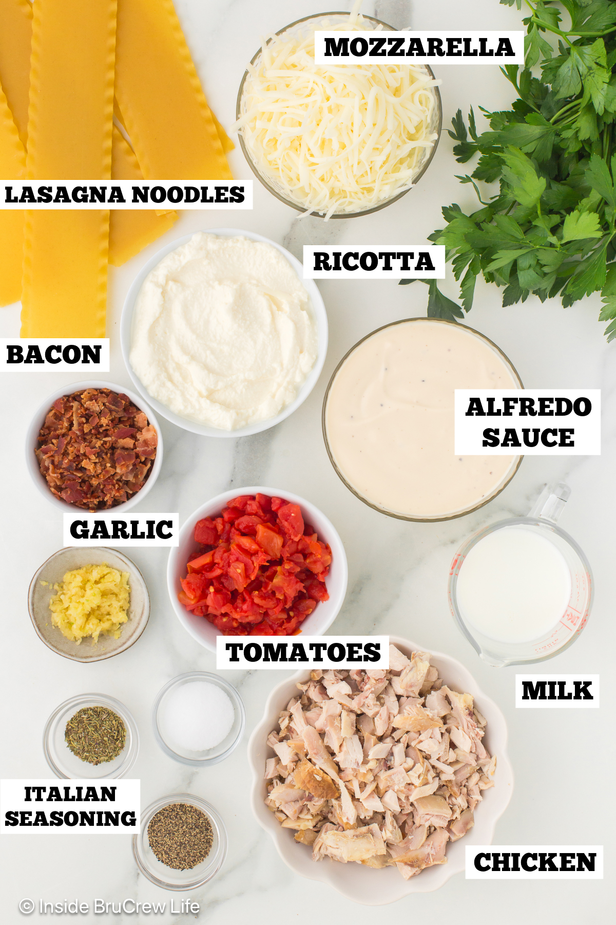 A white board with bowls of ingredients needed to make Alfredo roll ups.