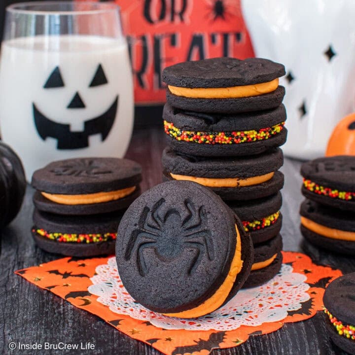 A stack of black cookies filled with orange creme filling.