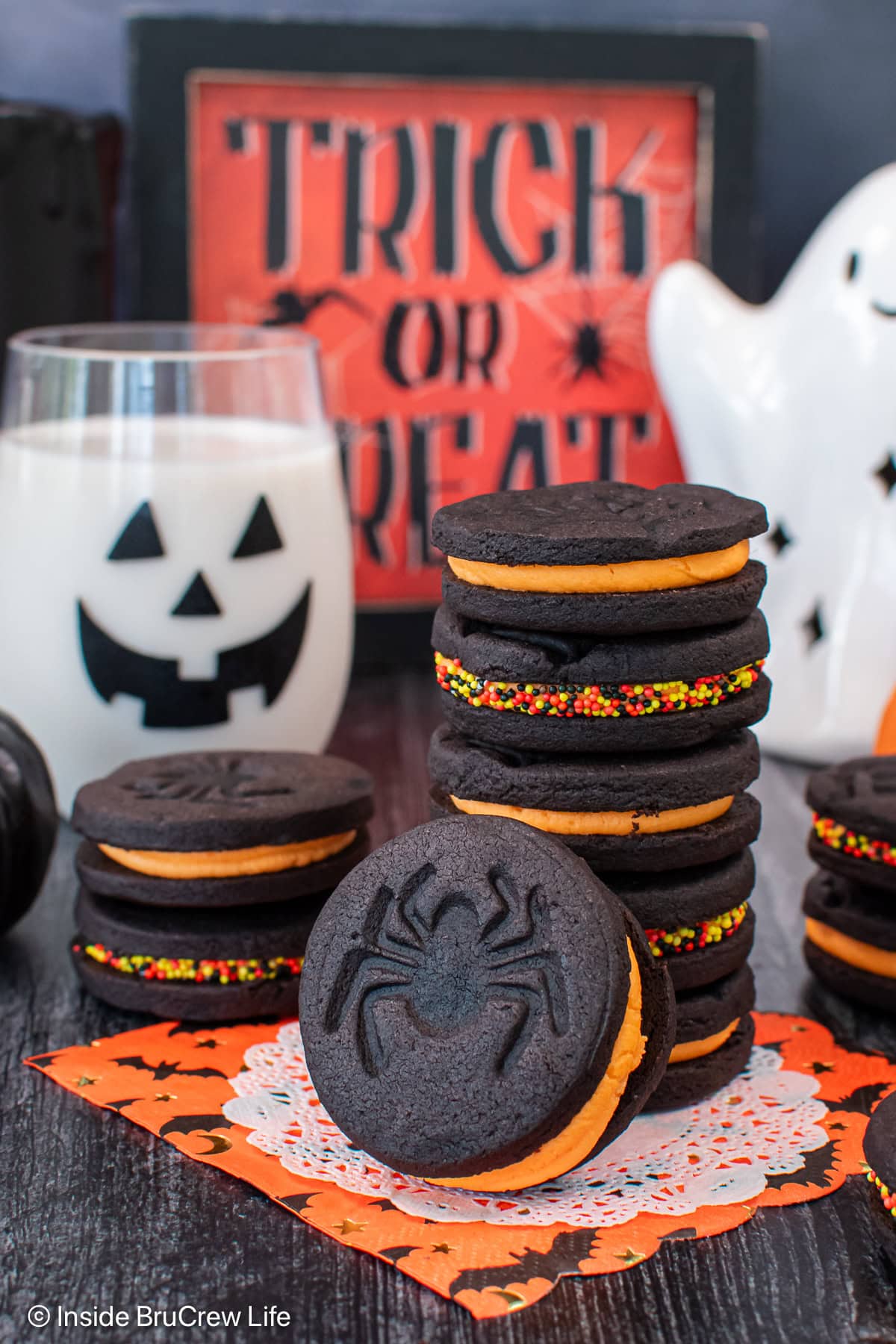 A stack of black cookies filled with orange creme filling.