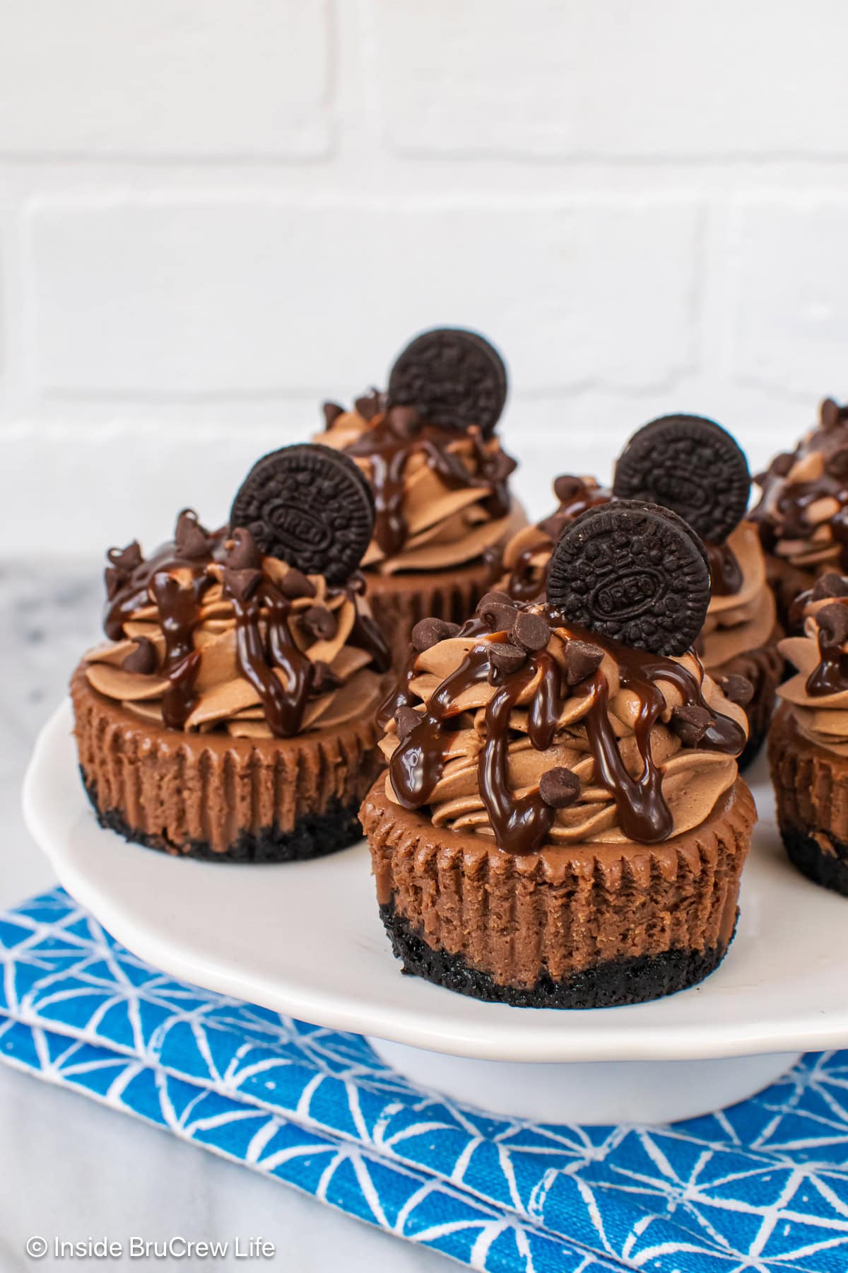 A white tray with tiny chocolate cheesecakes on it.