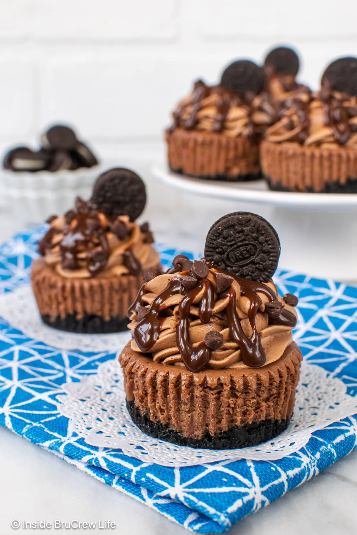 Triple chocolate cheesecakes on a white and blue towel.