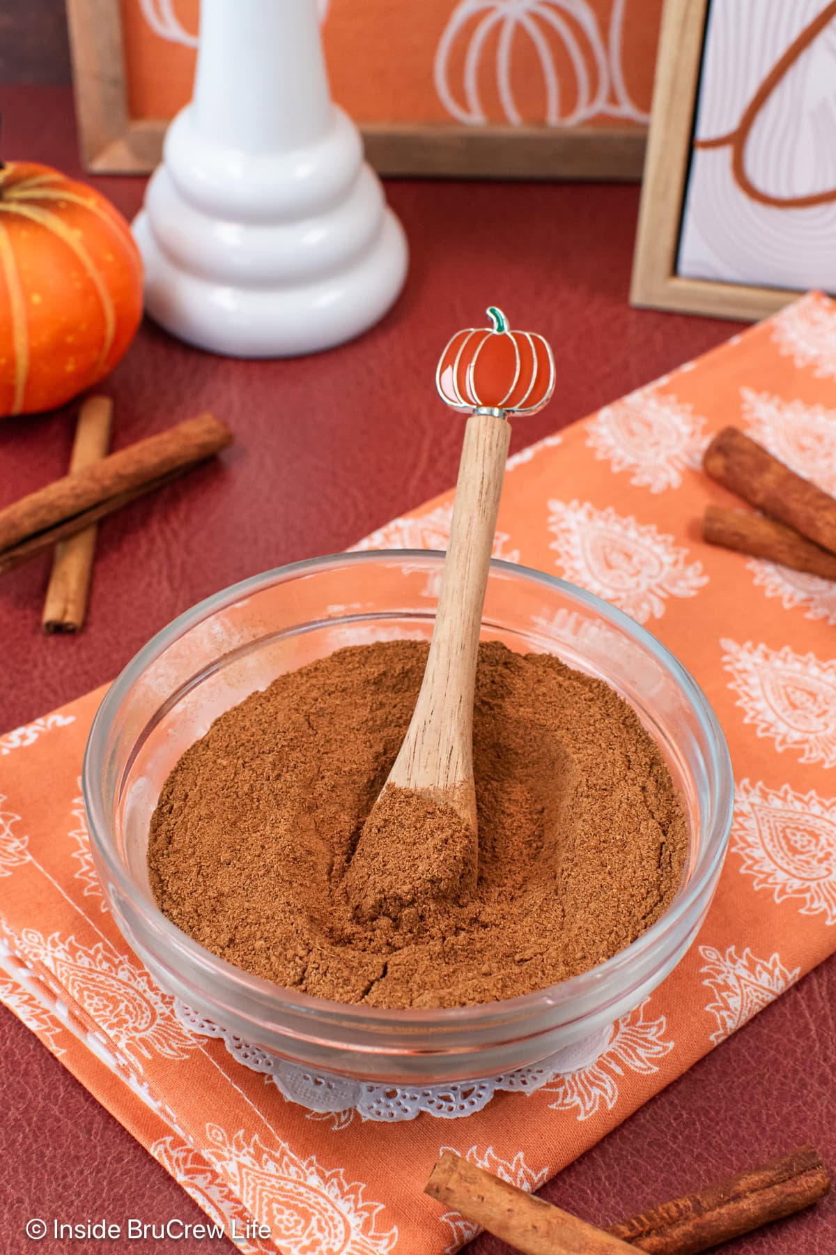 A bowl of spices with a cute pumpkin spoon.