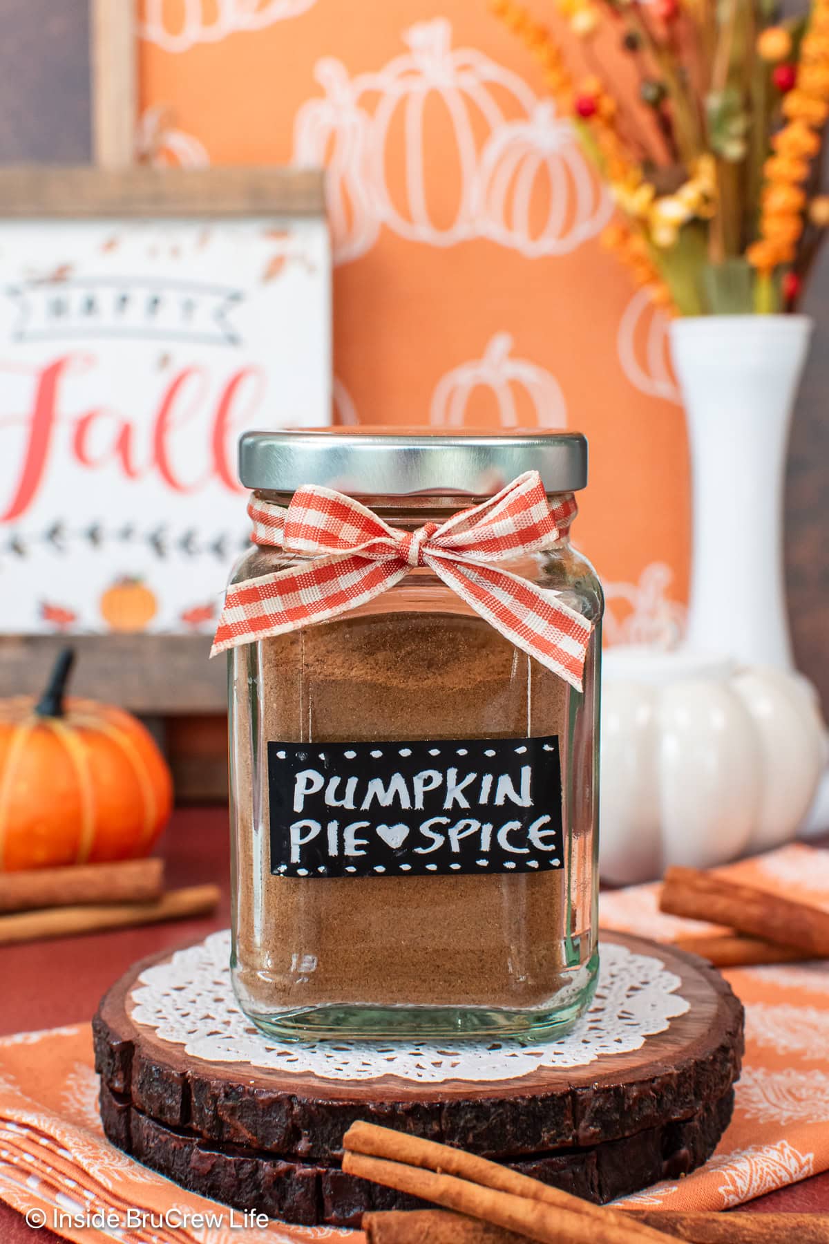 A spice jar with an orange ribbon filled with pumpkin pie spice.