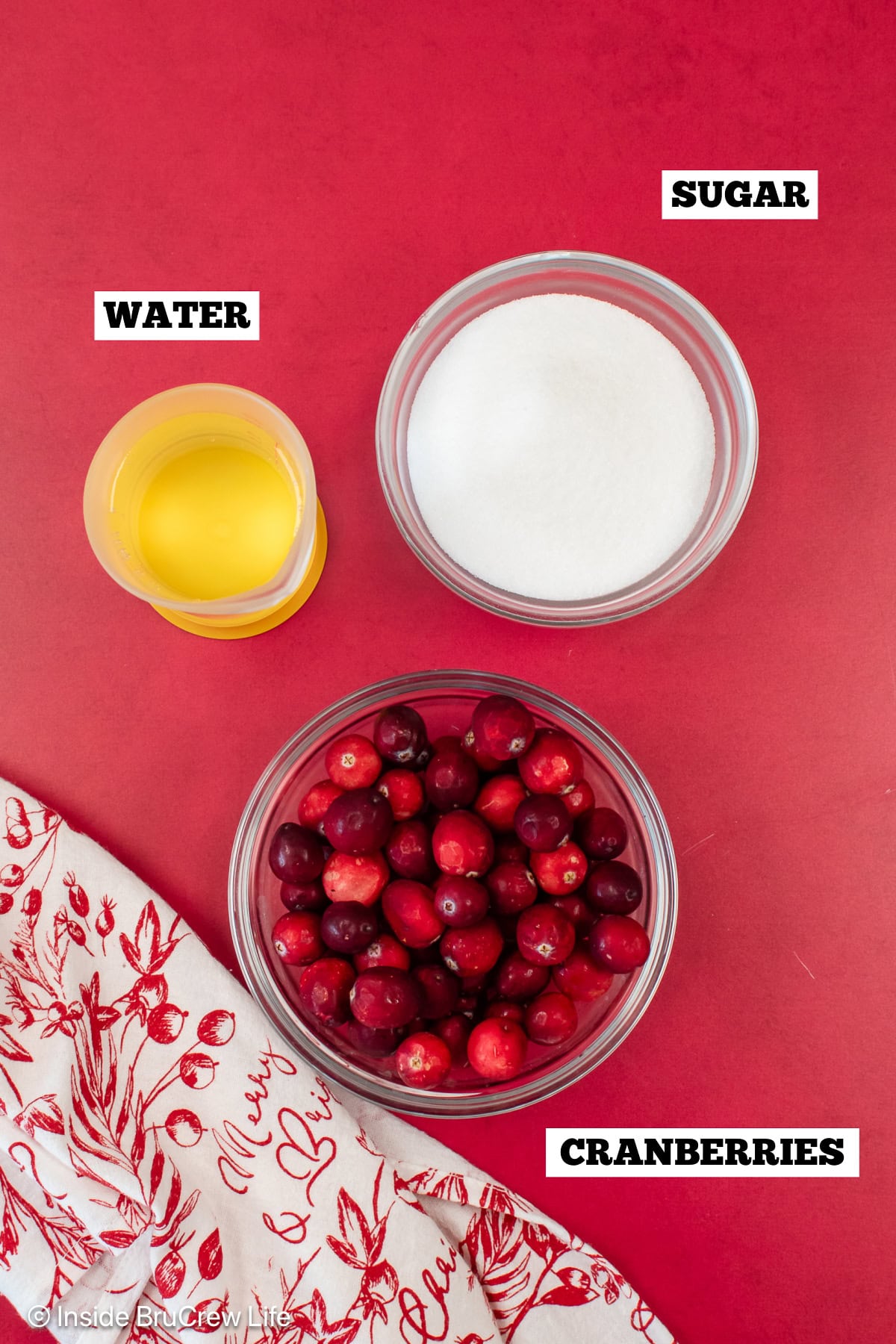 A red board with bowls of ingredients needed to make sugared berries.