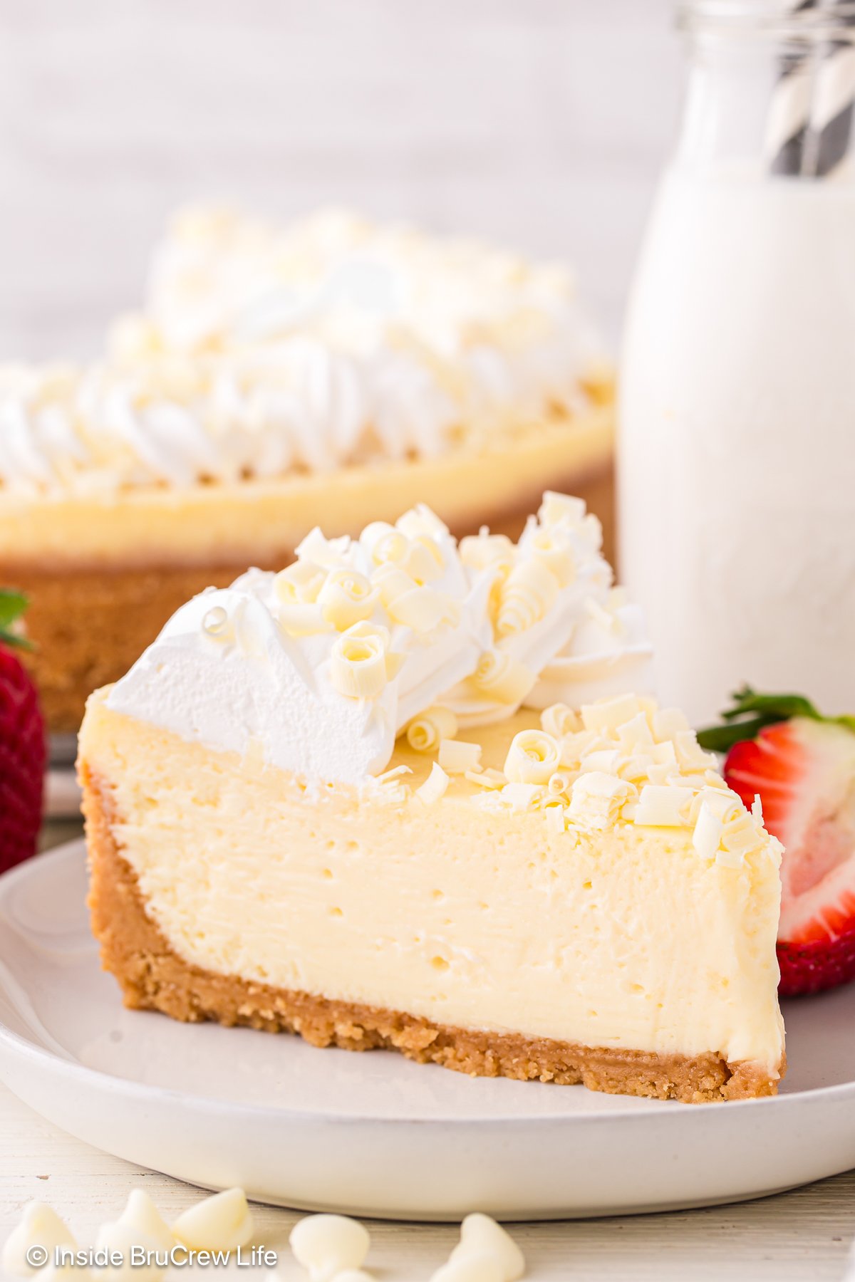 A slice of cheesecake with white chocolate curls on a plate.