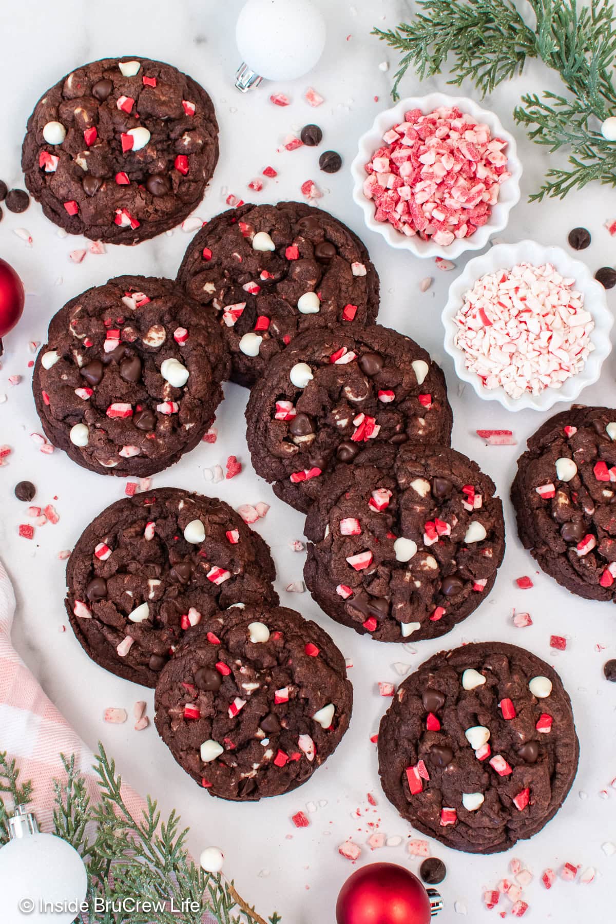 Chocolate cookies with peppermint chips on a white board.