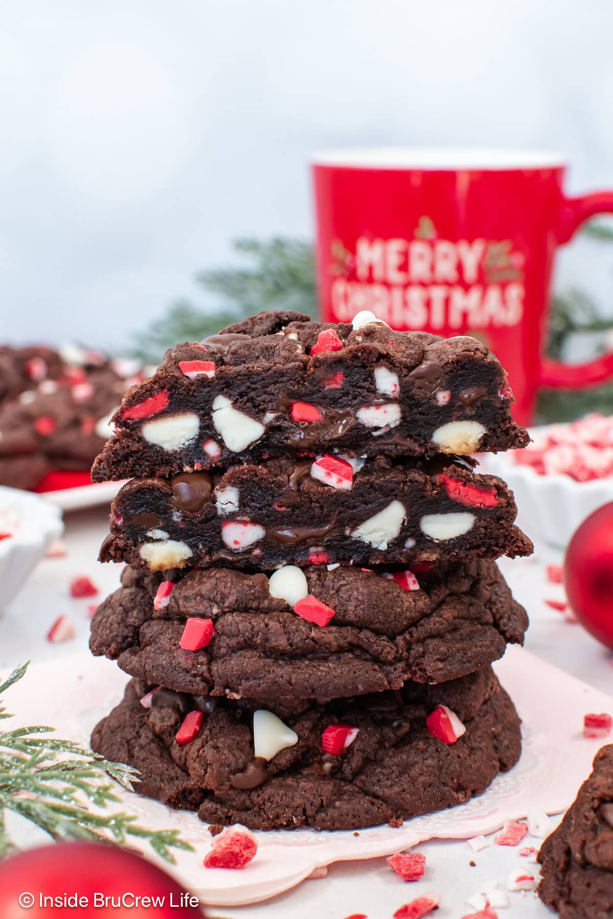 A stack of chocolate peppermint chip cookies with one cut in half.