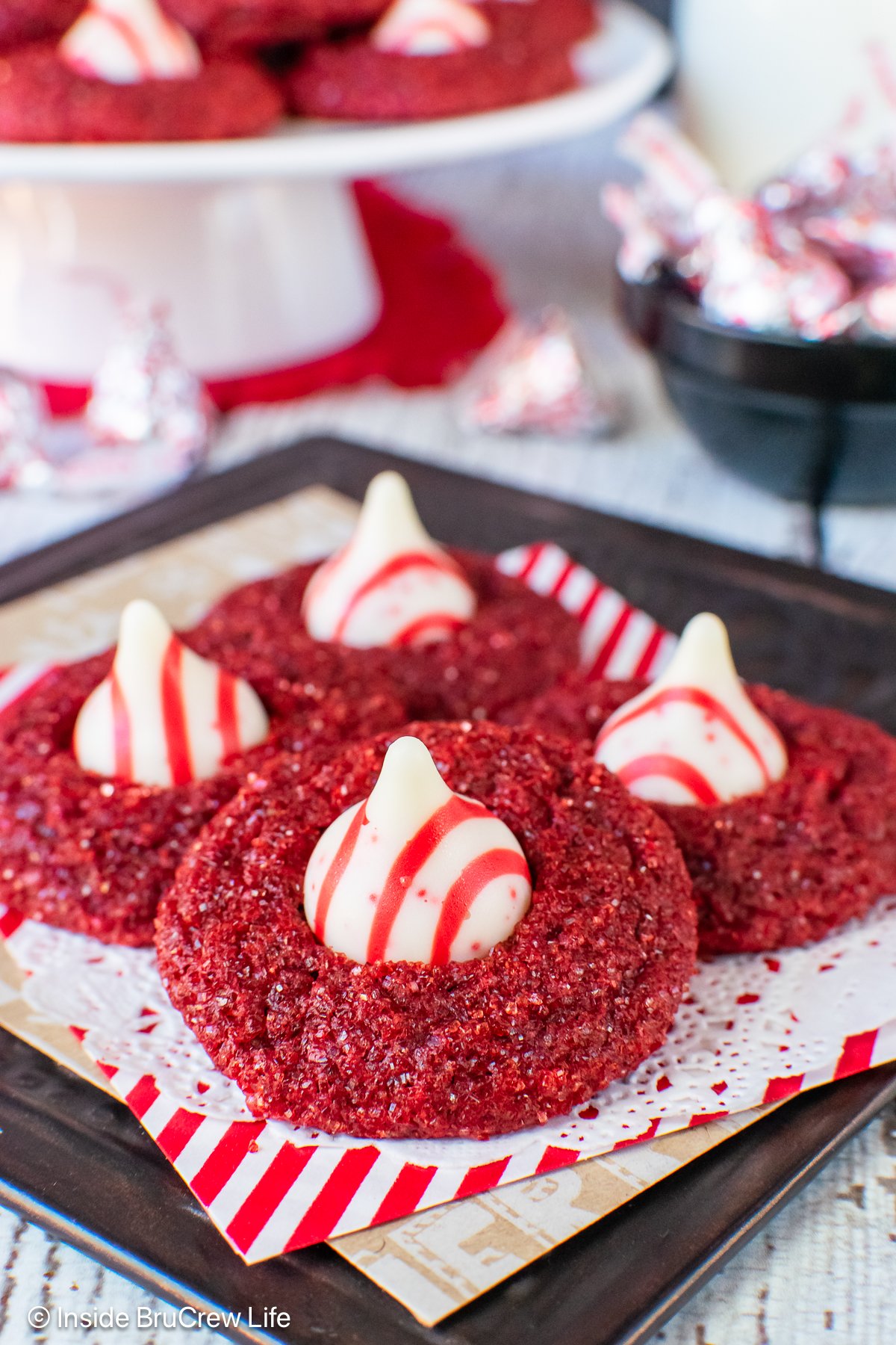 Sparkly red velvet blossom cookies with peppermint kisses on a tray.