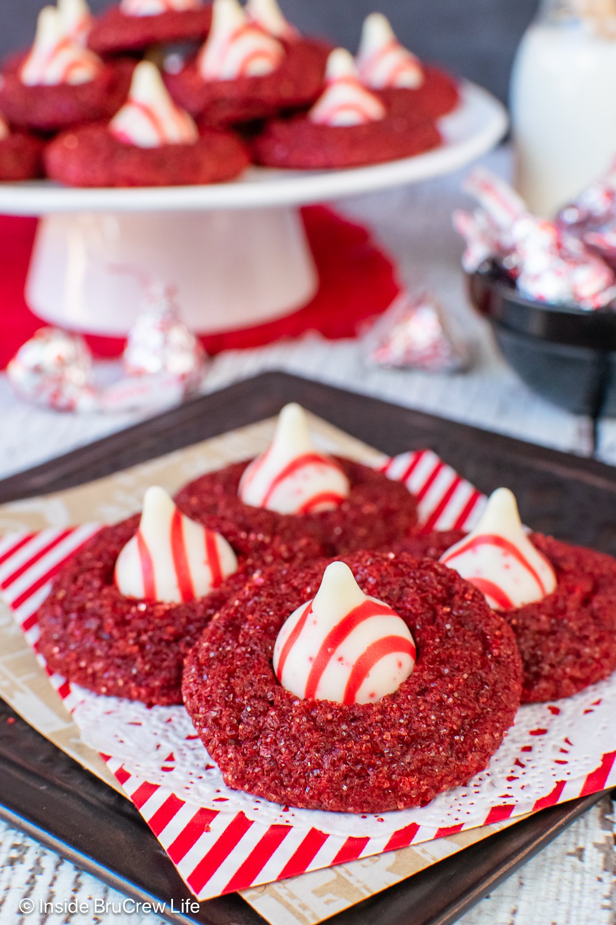 Sparkly red velvet blossom cookies with peppermint kisses on a tray.