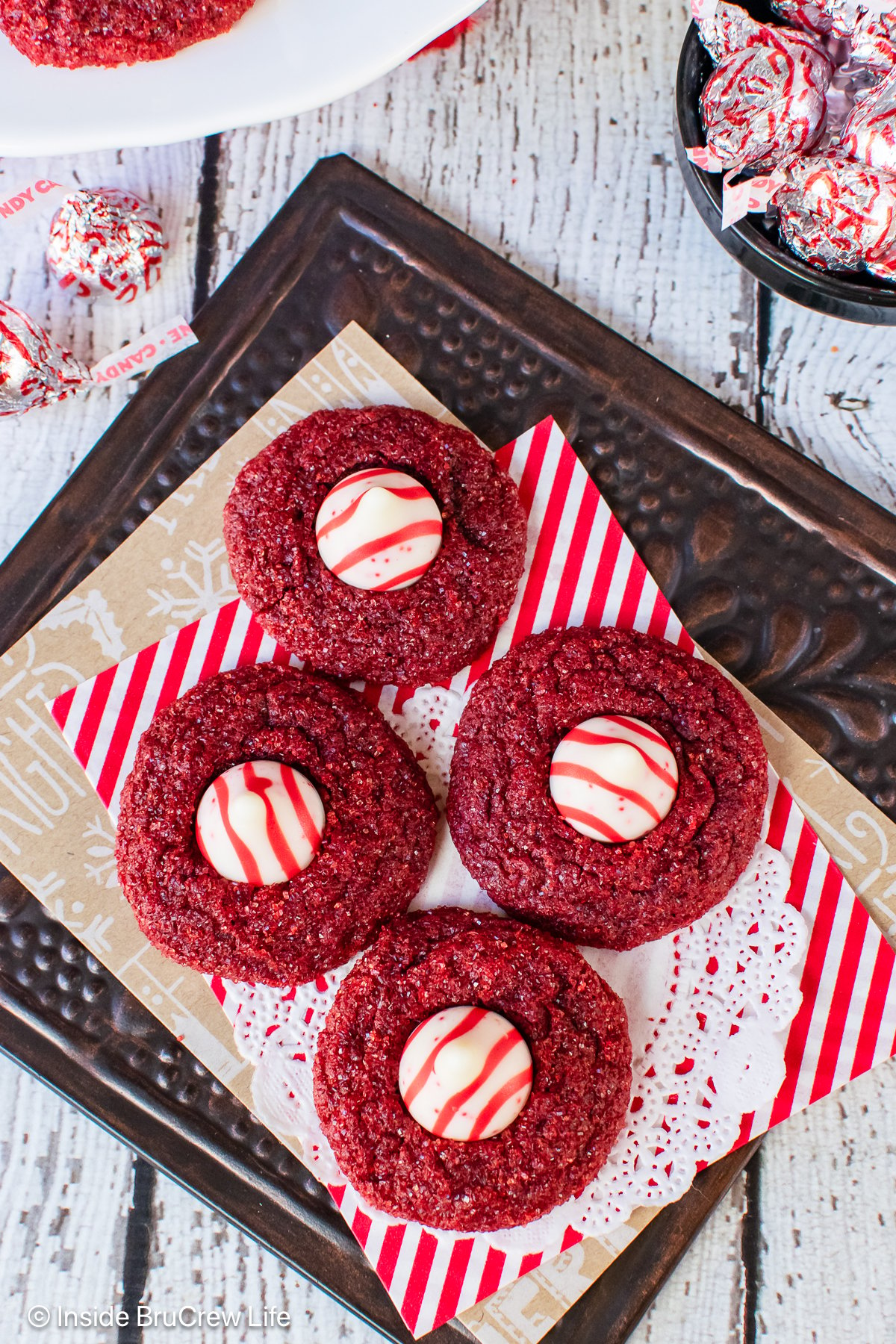 Four red velvet blossoms on a dark tray.