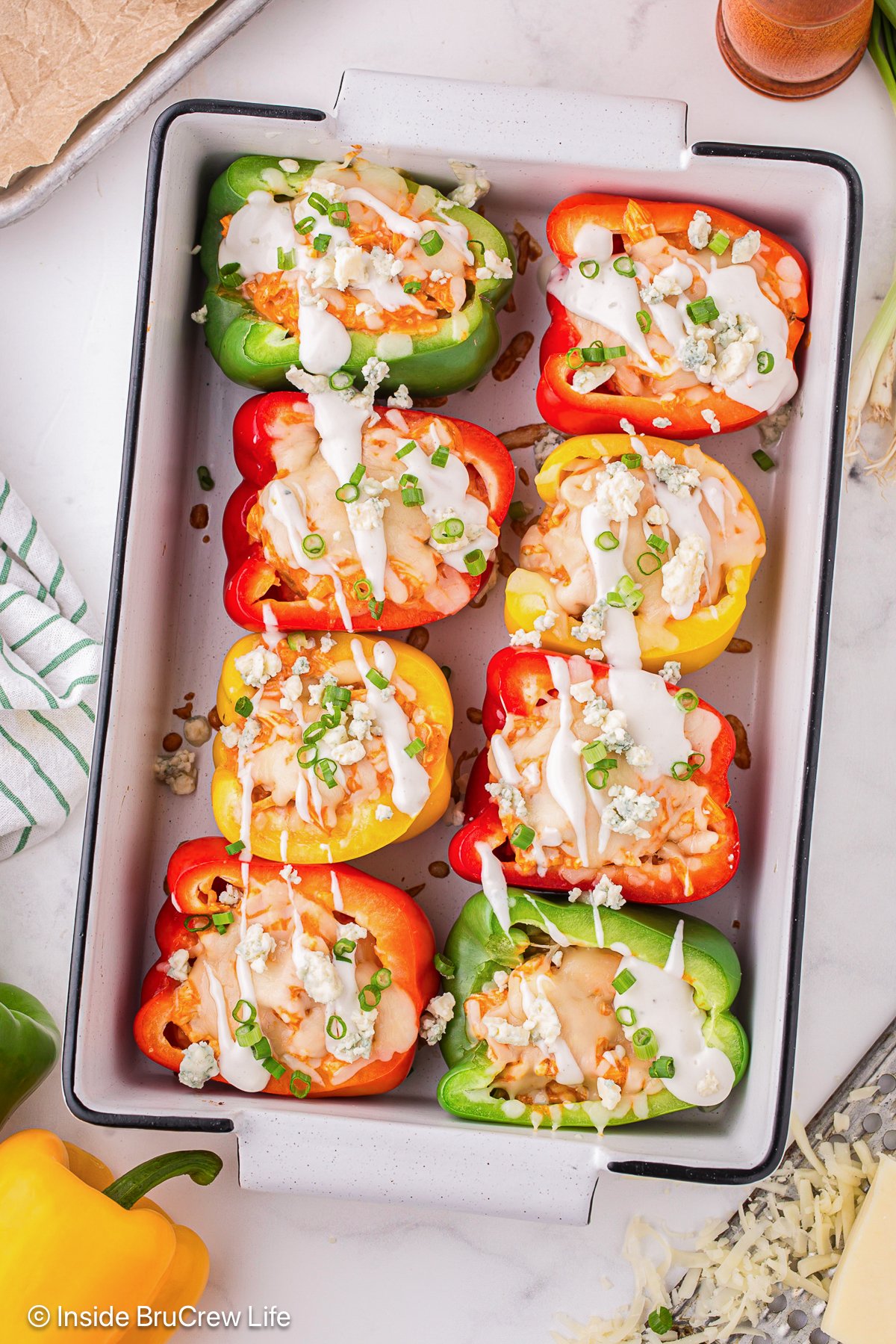 A white pan filled with stuffed peppers and drizzled with dressing.