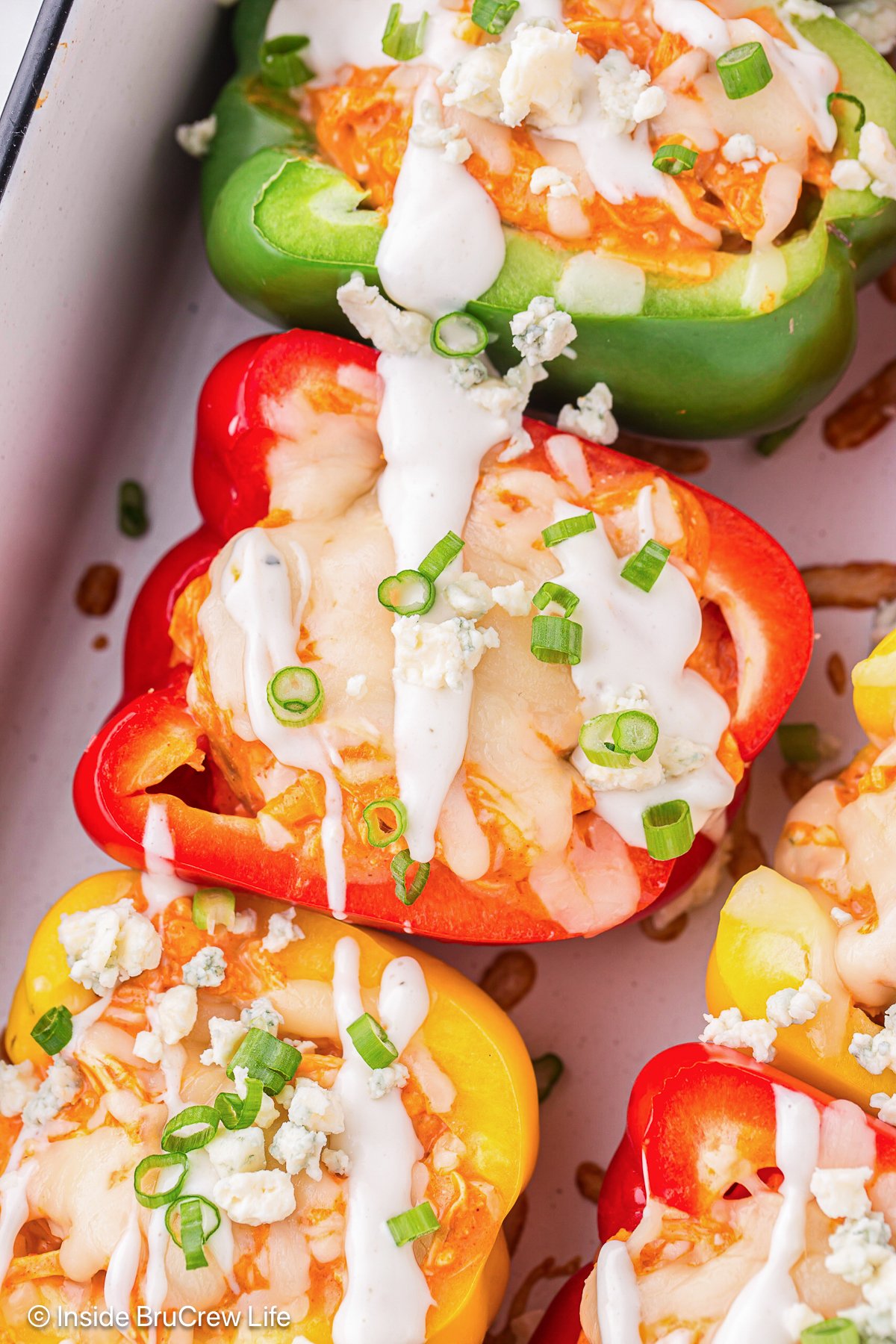 Stuffed chicken peppers topped with dressing and green onions.