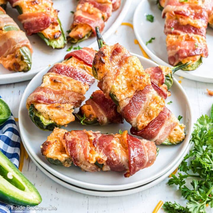 A plate with four stuffed jalapeno peppers stacked on it.