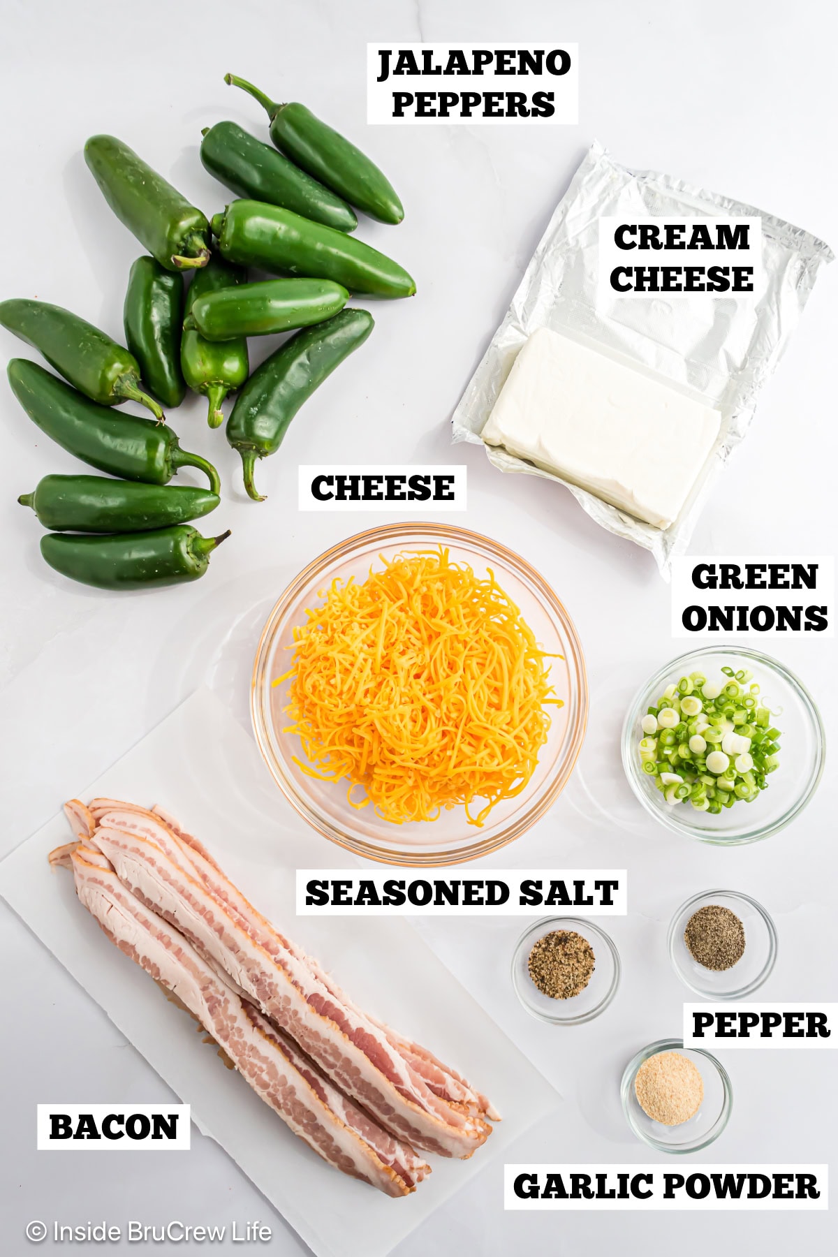 A white board with bowls of ingredients needed to make stuffed jalapenos.