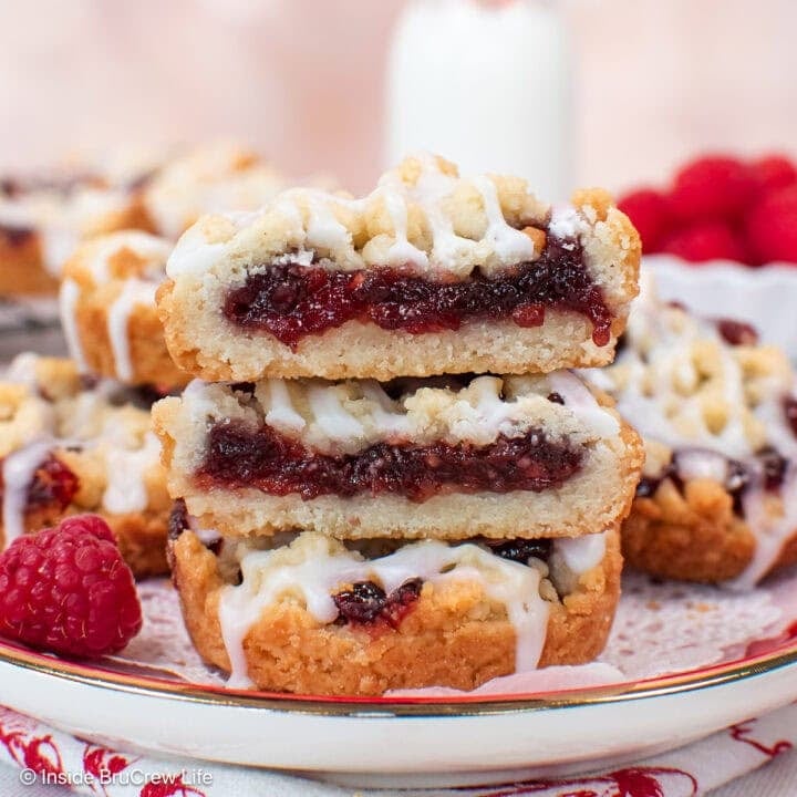 A stack of raspberry cookies cut in half showing the fruit filling.