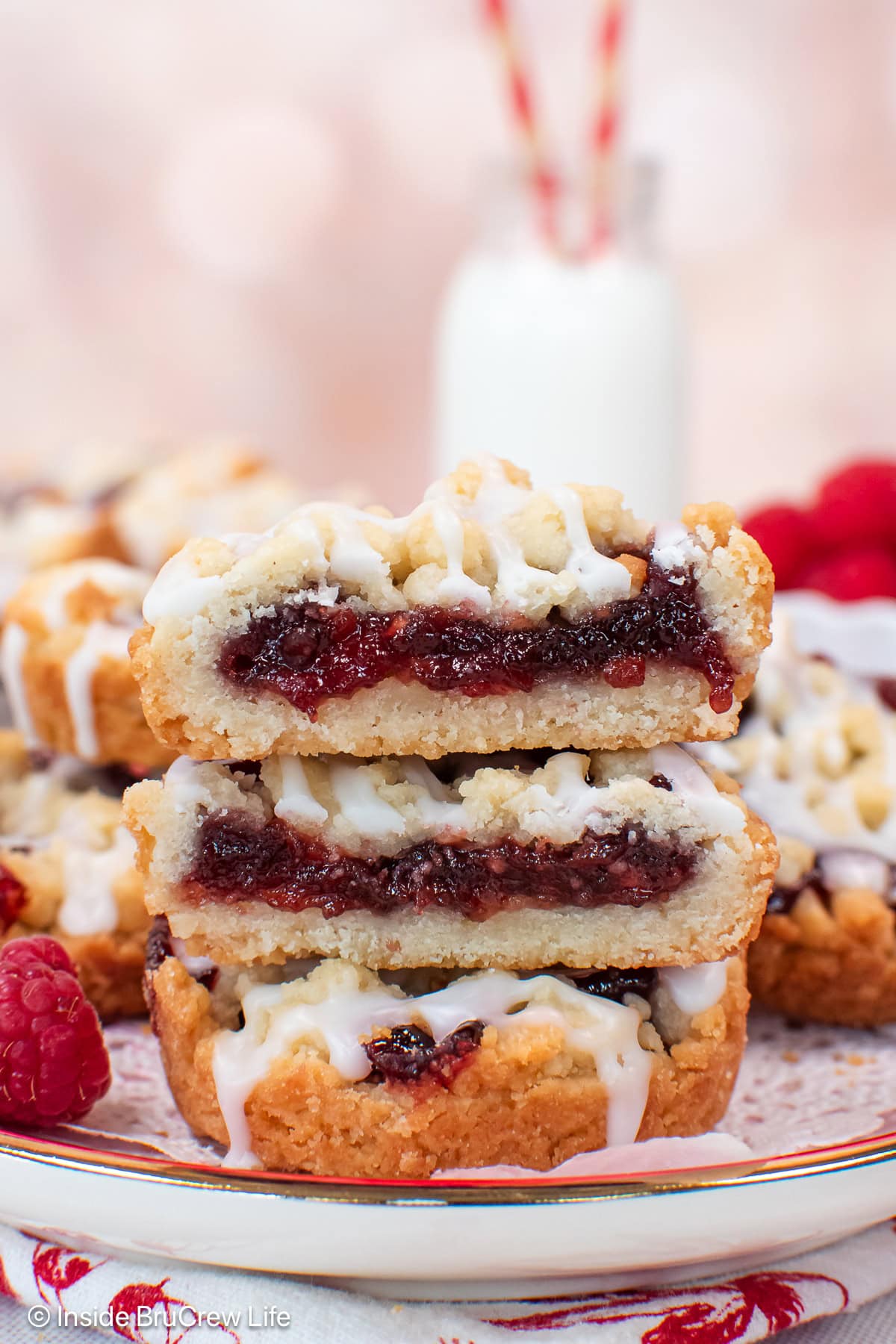 A stack of raspberry cookies cut in half showing the fruit filling.