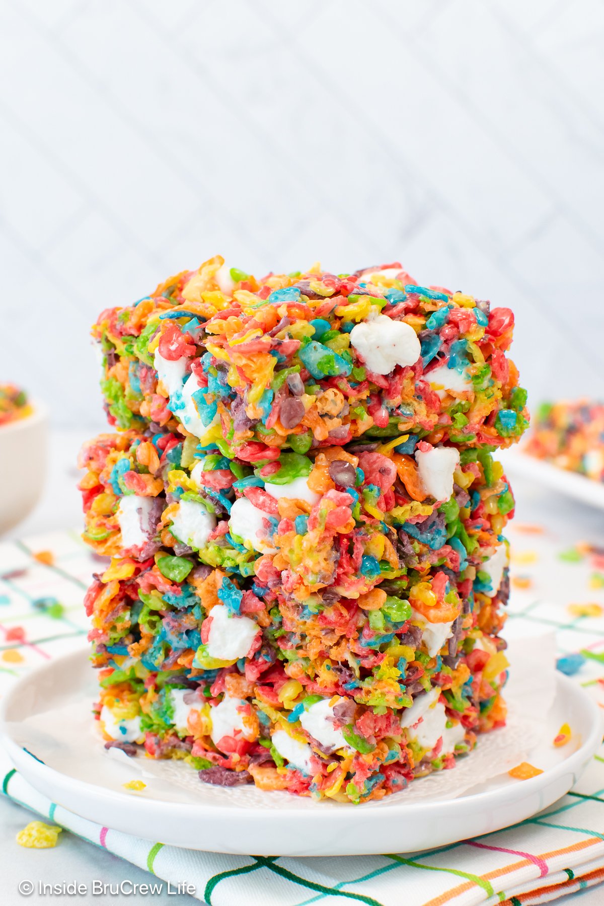 A stack of fruity pebbles crispy treats on a white plate.