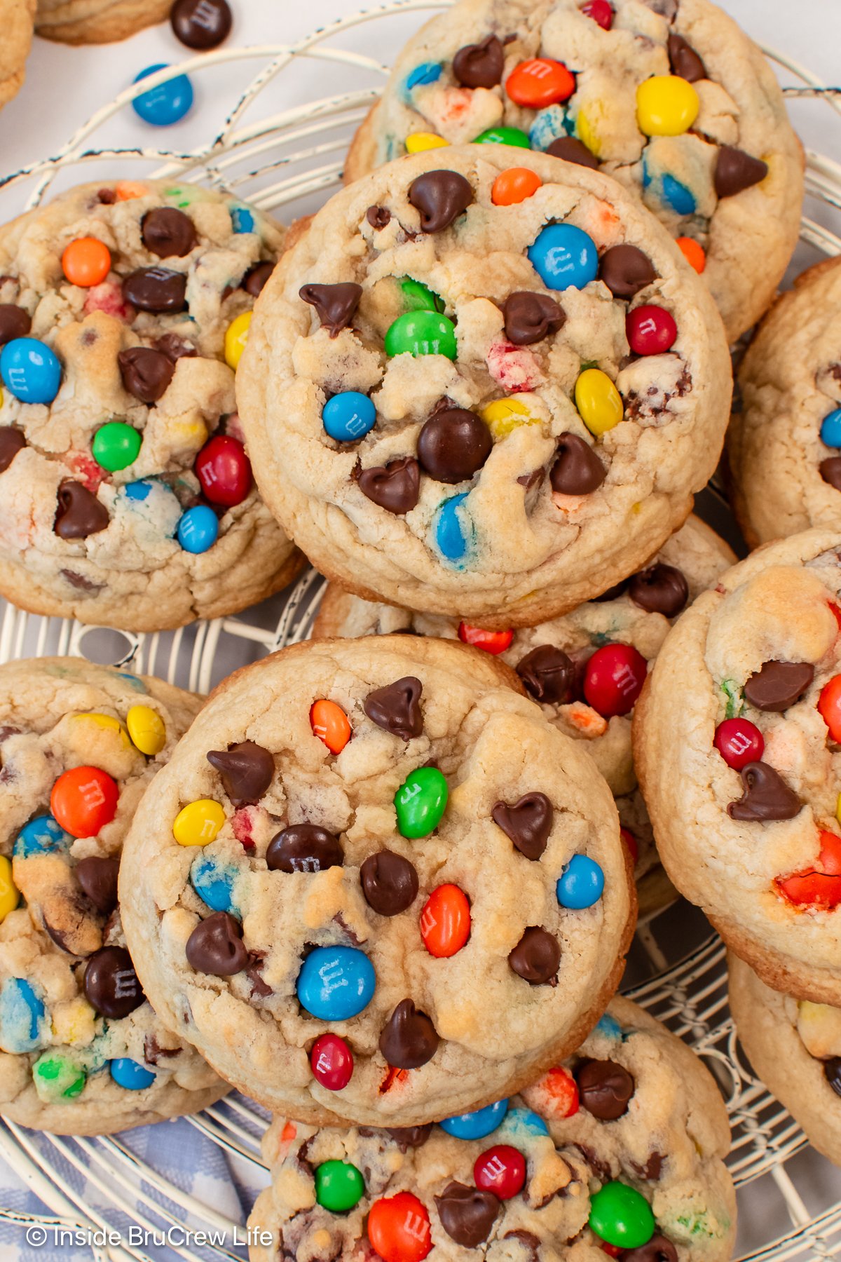 Chocolate chip cookies with M&M candies on a cooling rack.