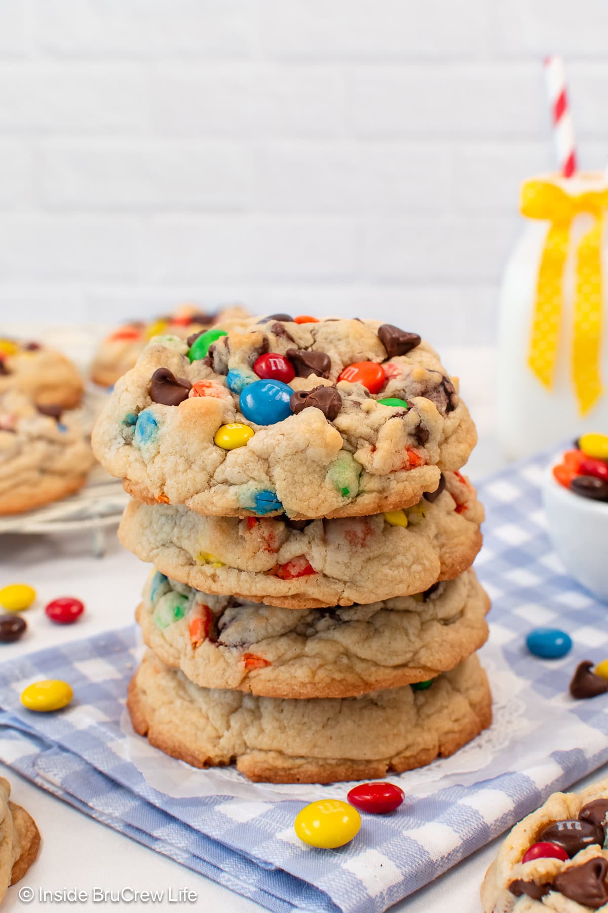 A stack of four chocolate chip M&M cookies on a blue and white towel.