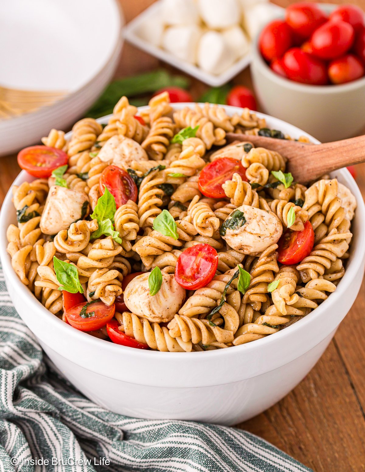 A white bowl filled with a Caprese pasta salad.