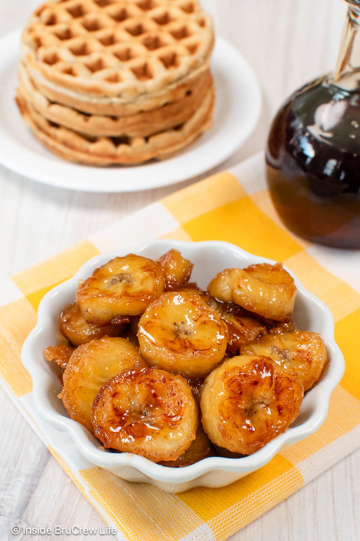 A bowl of caramelized bananas on a white and yellow towel.