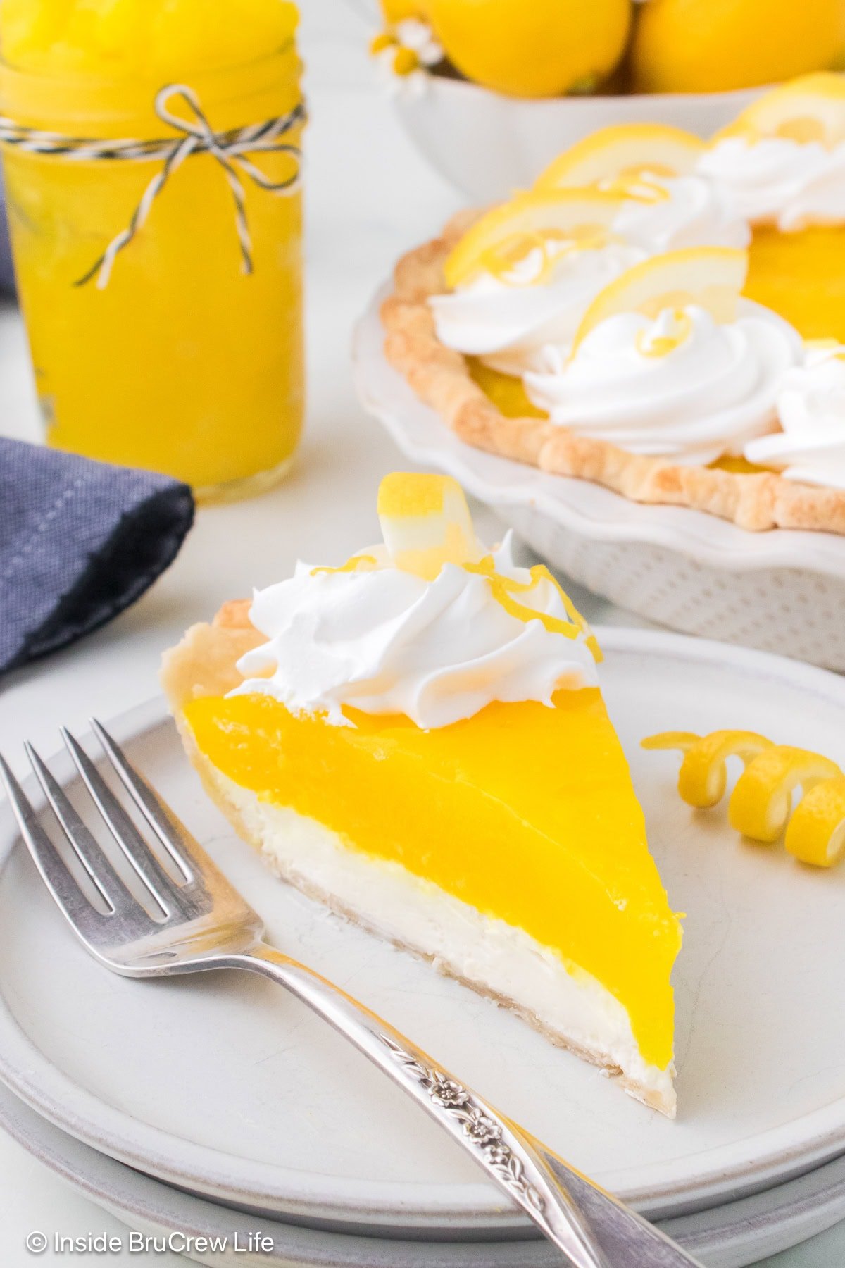 A slice of layered lemon supreme pie on a white plate.