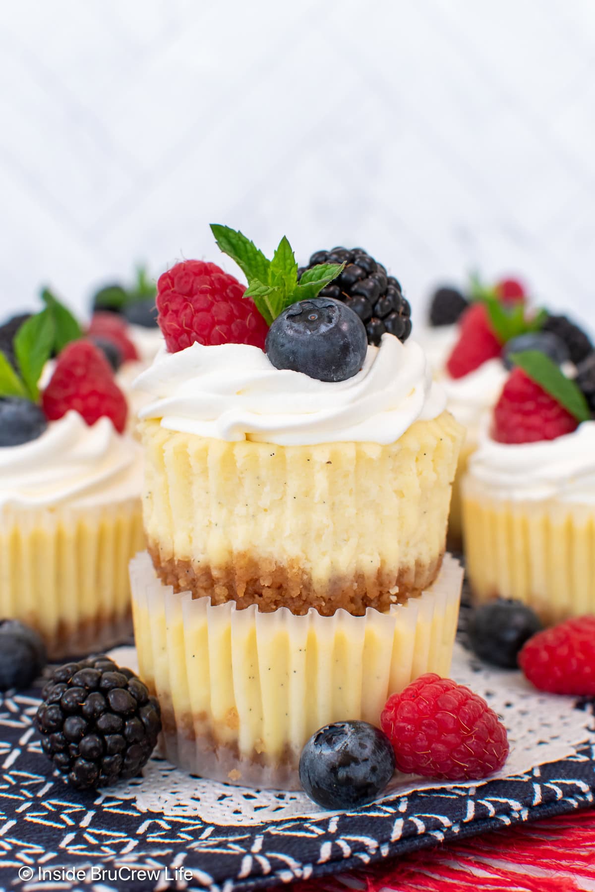 Mini cheesecakes stacked on top of each other and decorated with whipped cream and berries.