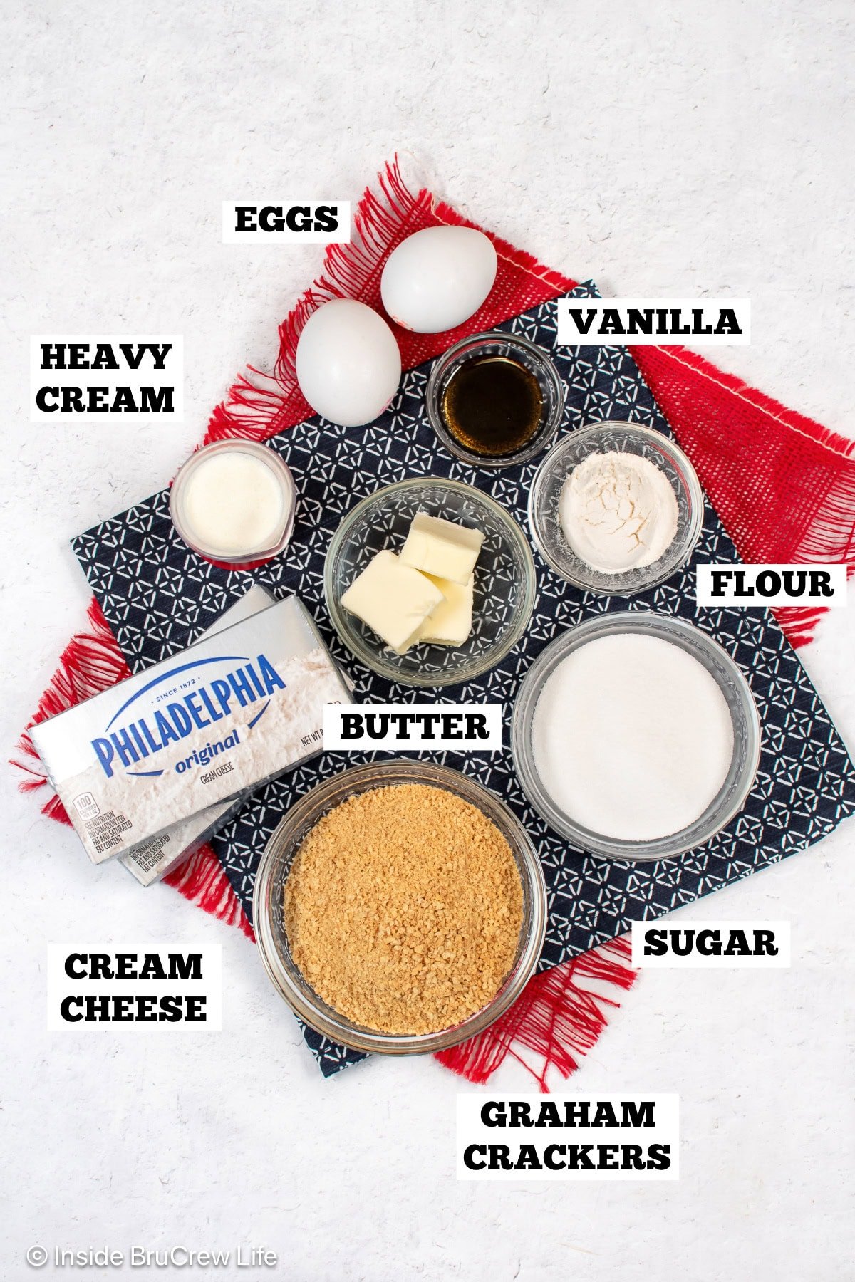 A white board with bowls of ingredients needed to make cheesecakes in a muffin pan.