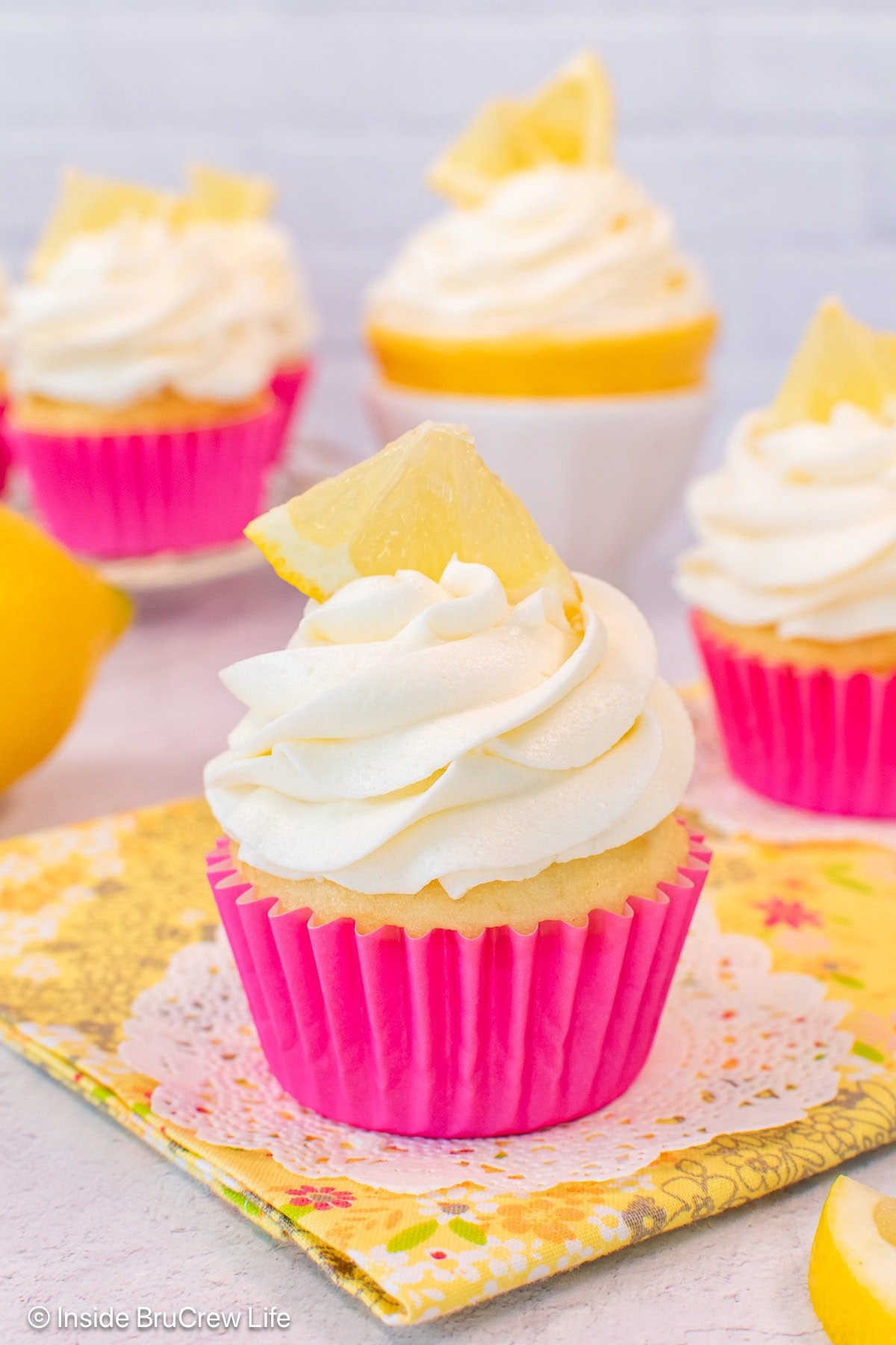 A cupcake in a pink wrapper with a swirl of lemon buttercream frosting.