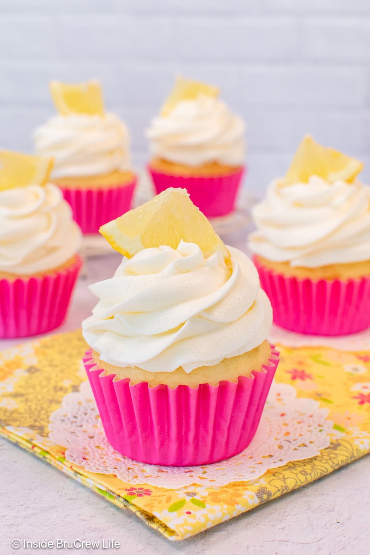Cupcakes in pink wrappers with lemon frosting on top.