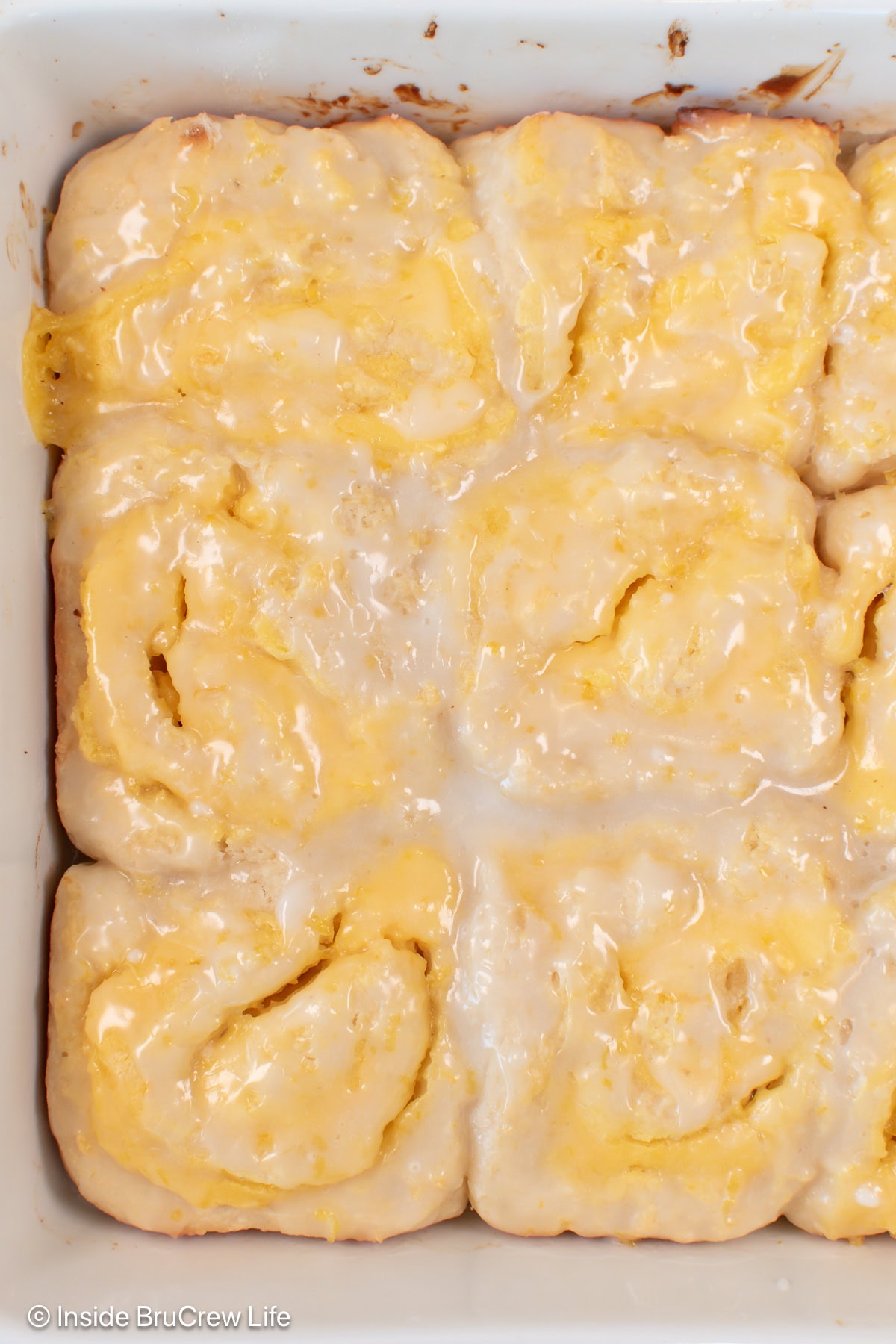 Glazed lemon rolls in a white baking dish.