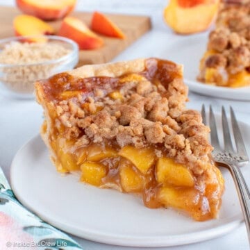 A slice of peach crumble pie on a white plate.