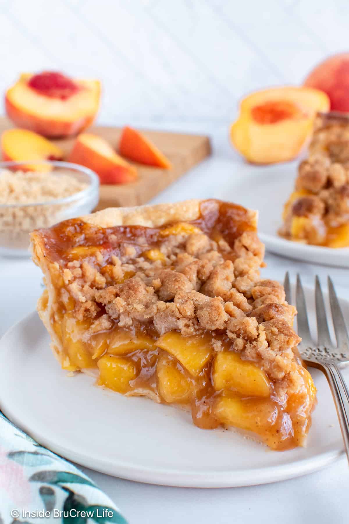 A slice of peach crumble pie on a white plate.
