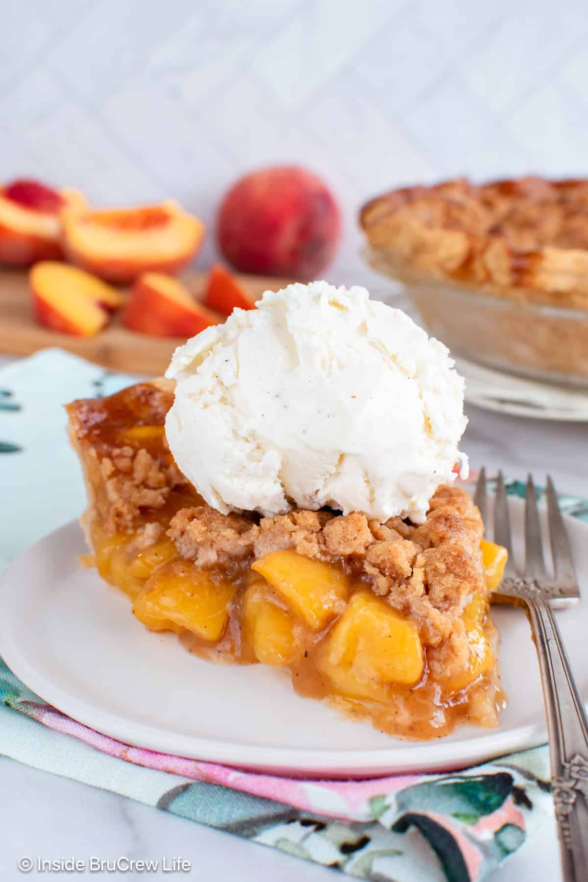 A slice of peach pie with vanilla ice cream on top.