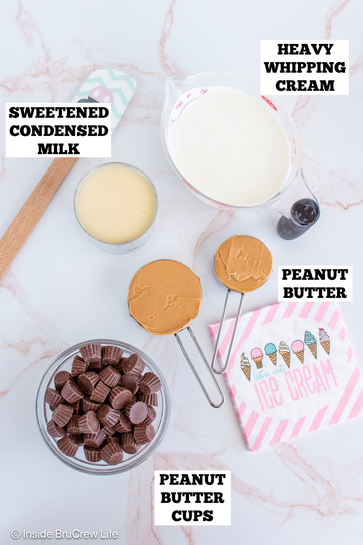 A white board with bowls of ingredients needed to make no churn ice cream with peanut butter.