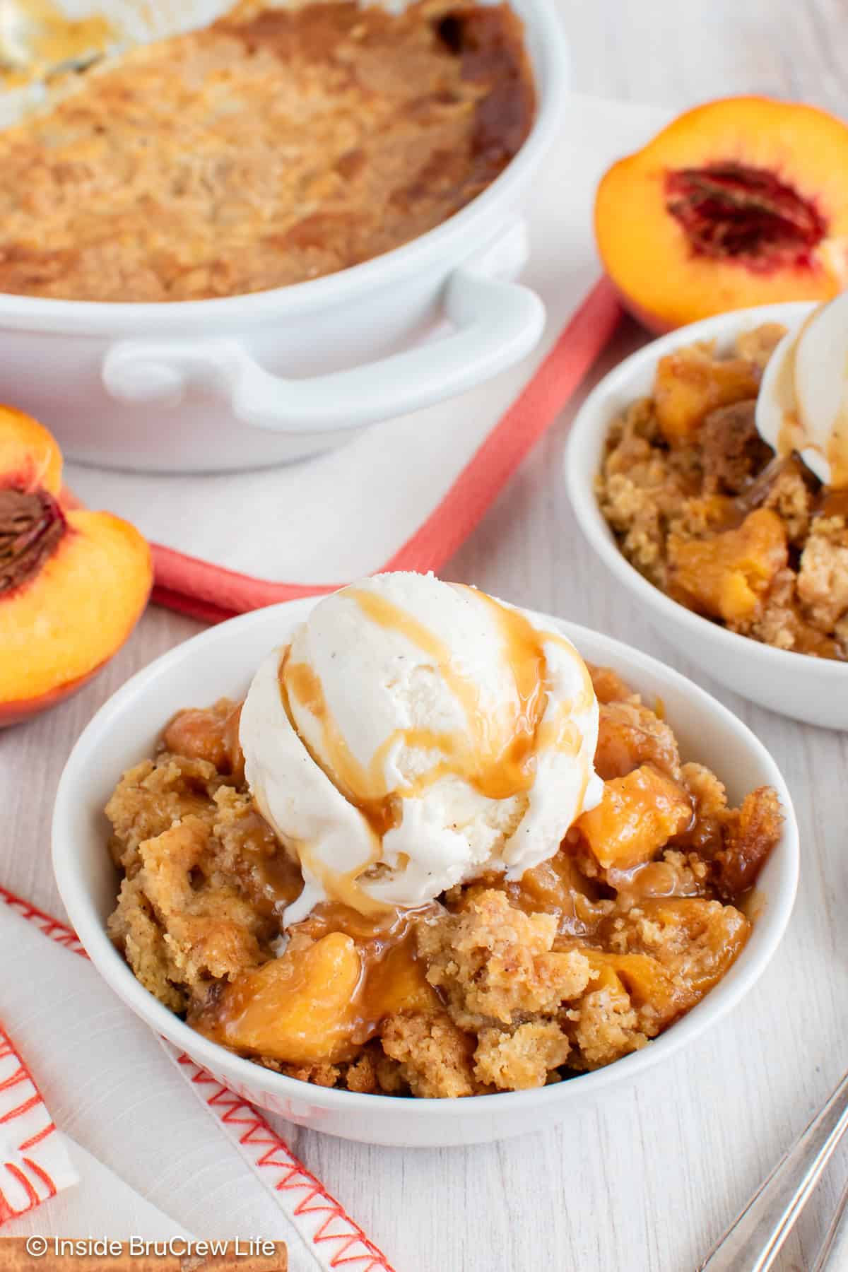 A bowl of peach dump cake with vanilla ice cream and caramel drizzles.