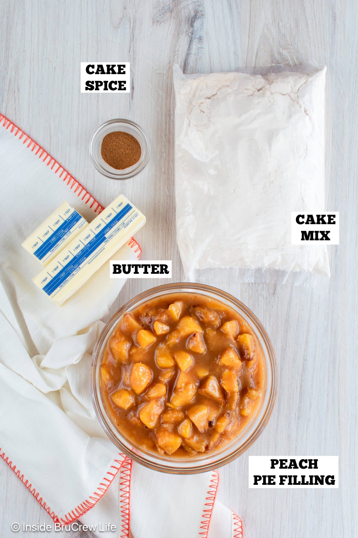 A white board with bowls of ingredients needed to make dump cake with peach pie filling.