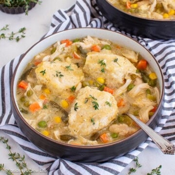 A bowl of crockpot chicken and dumplings on a striped towel.