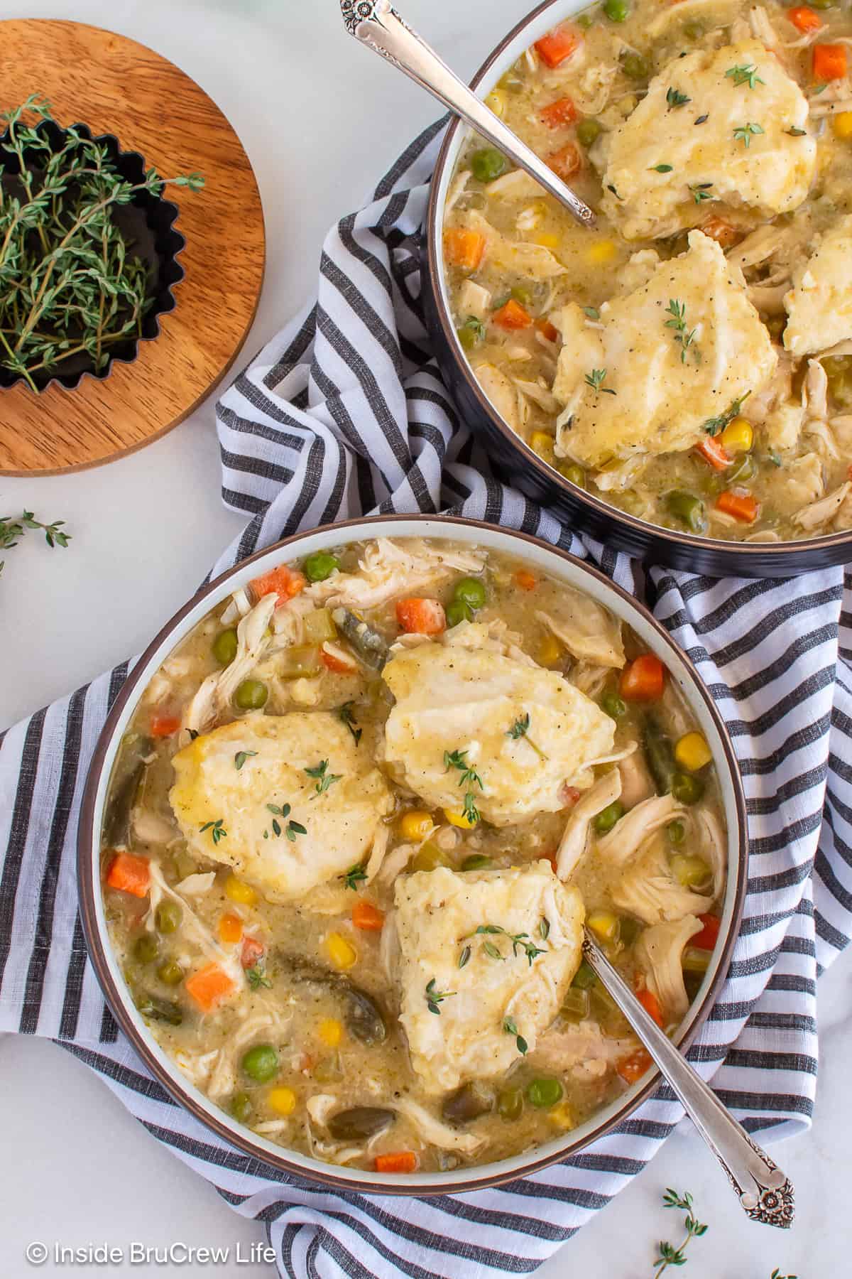 Two bowls filled with chicken and dumplings on a striped towel.