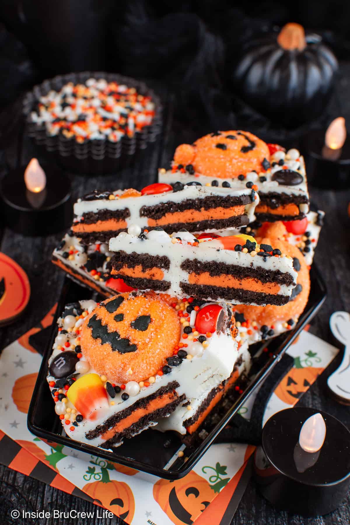 A tray of chocolate bark filled with Halloween cookies and candies.