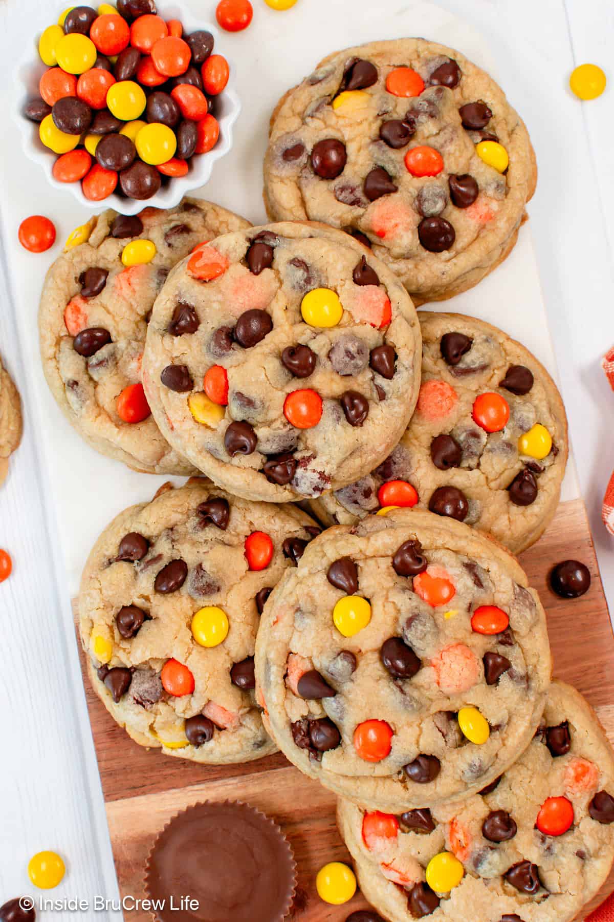 Overhead view of Reese's chocolate chip cookies piled on a countertop next to a bowl of Reese's pieces.