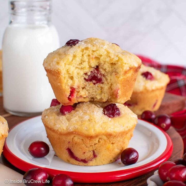 Two cranberry orange muffins stacked on top of each other with a bite out of the top one.