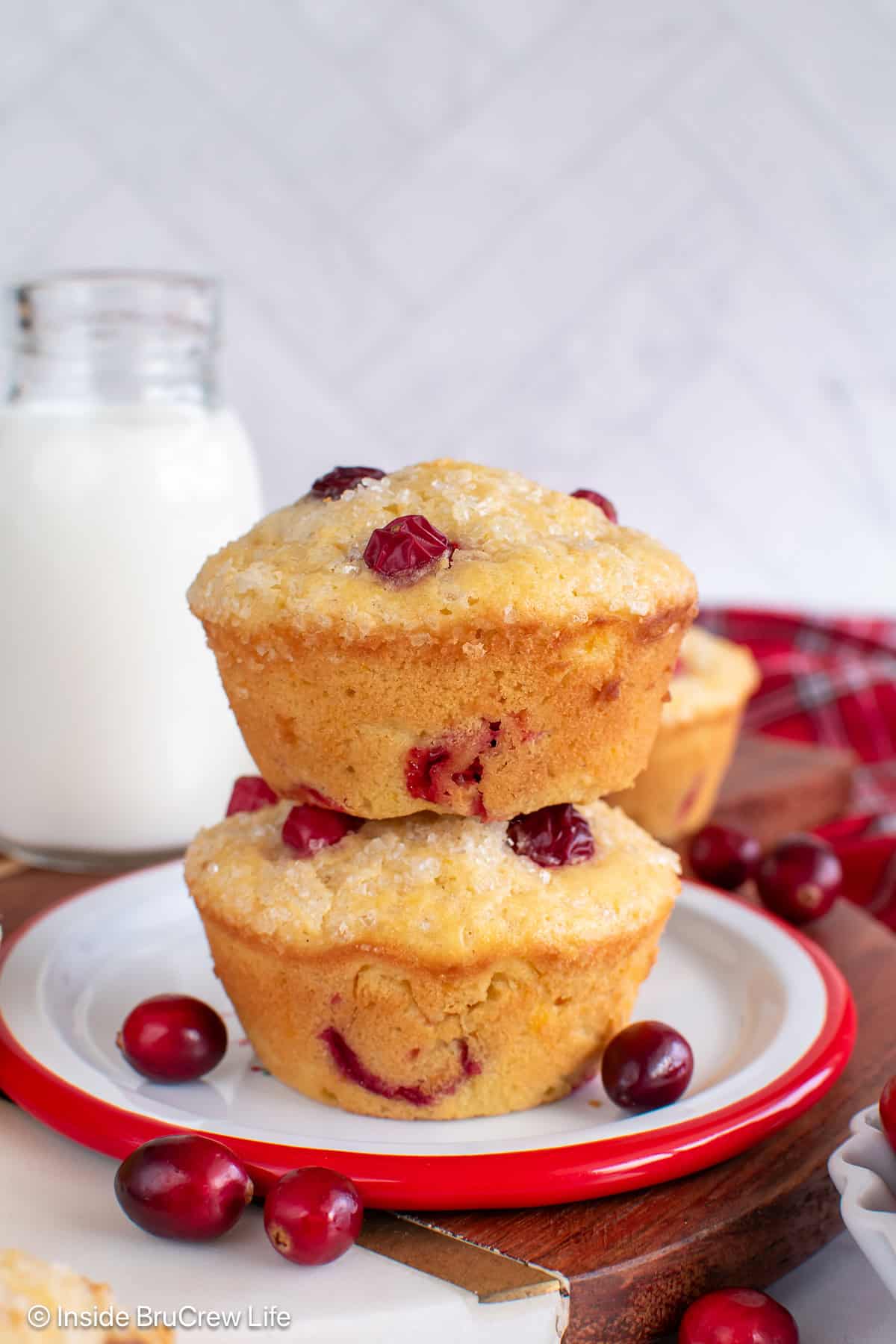 Two cranberry orange muffins stacked on a white plate.
