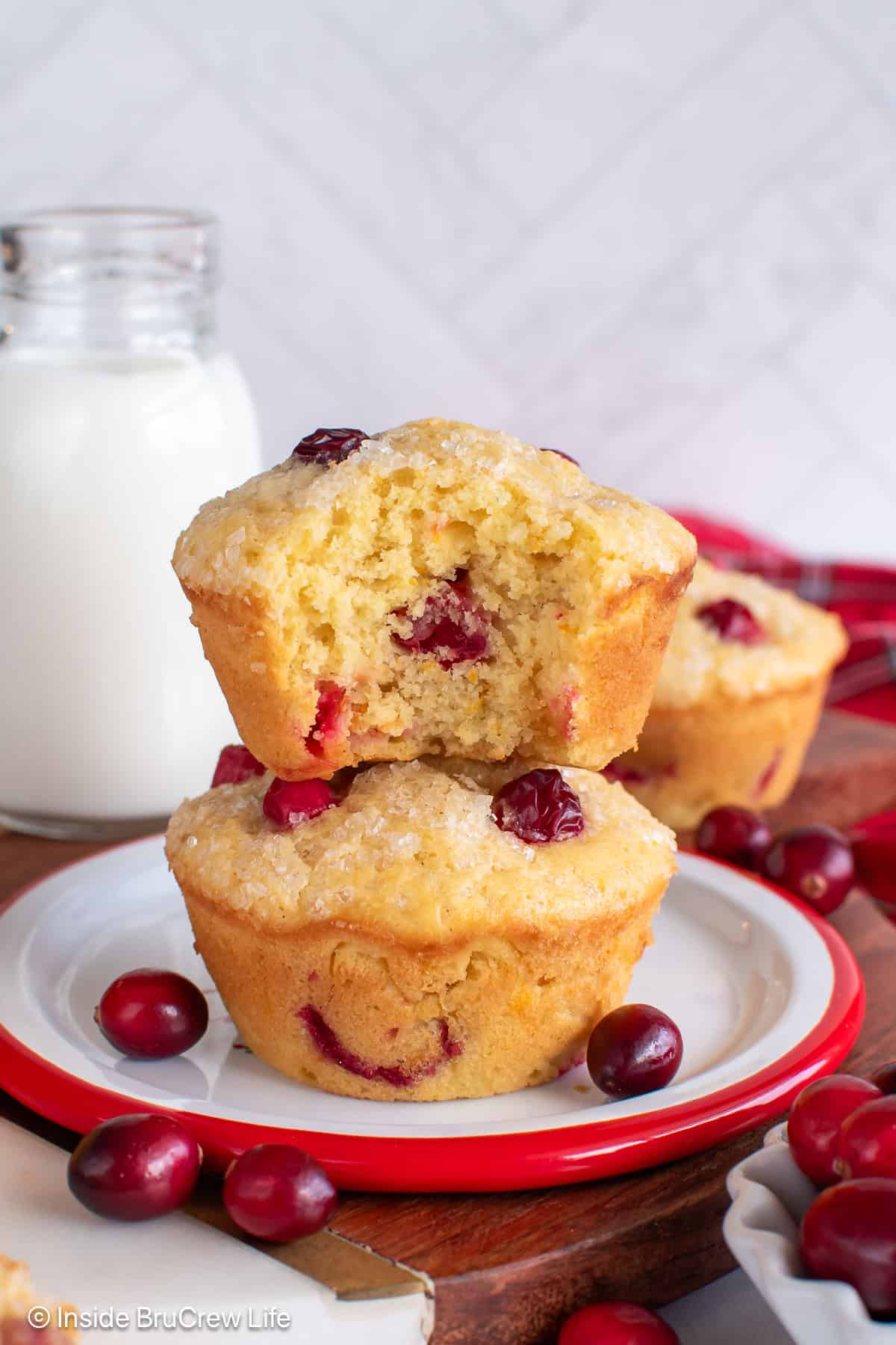 Two cranberry orange muffins stacked on top of each other with a bite out of the top one.