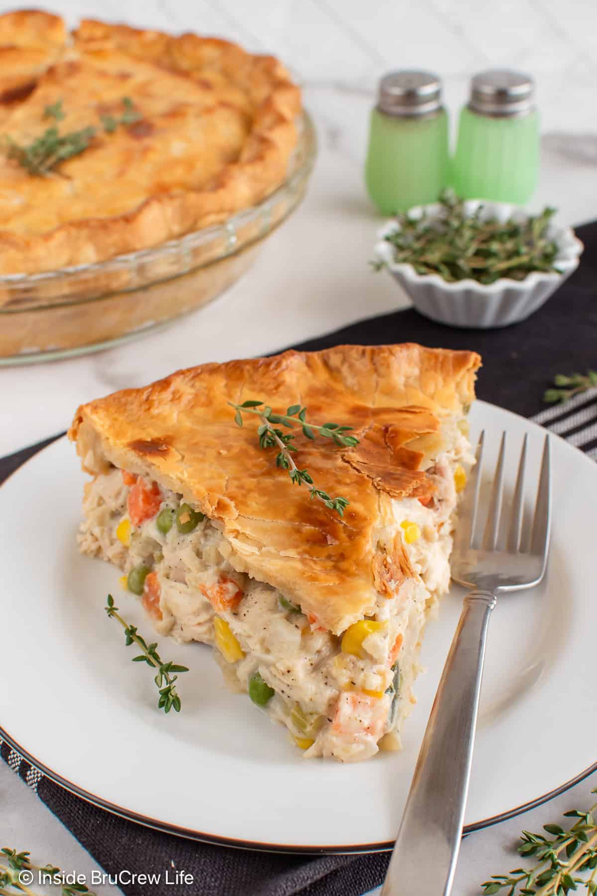 A white plate with a fork and a slice of homemade chicken pot pie.